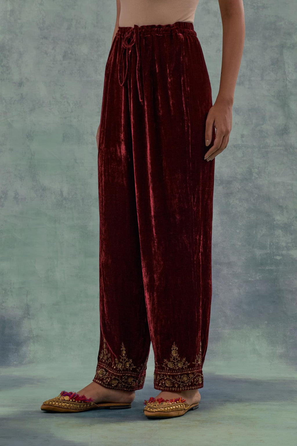 Deep maroon velvet straight pants. The hem is highlighted with hand-embroidered bead, sequins and zari motifs.