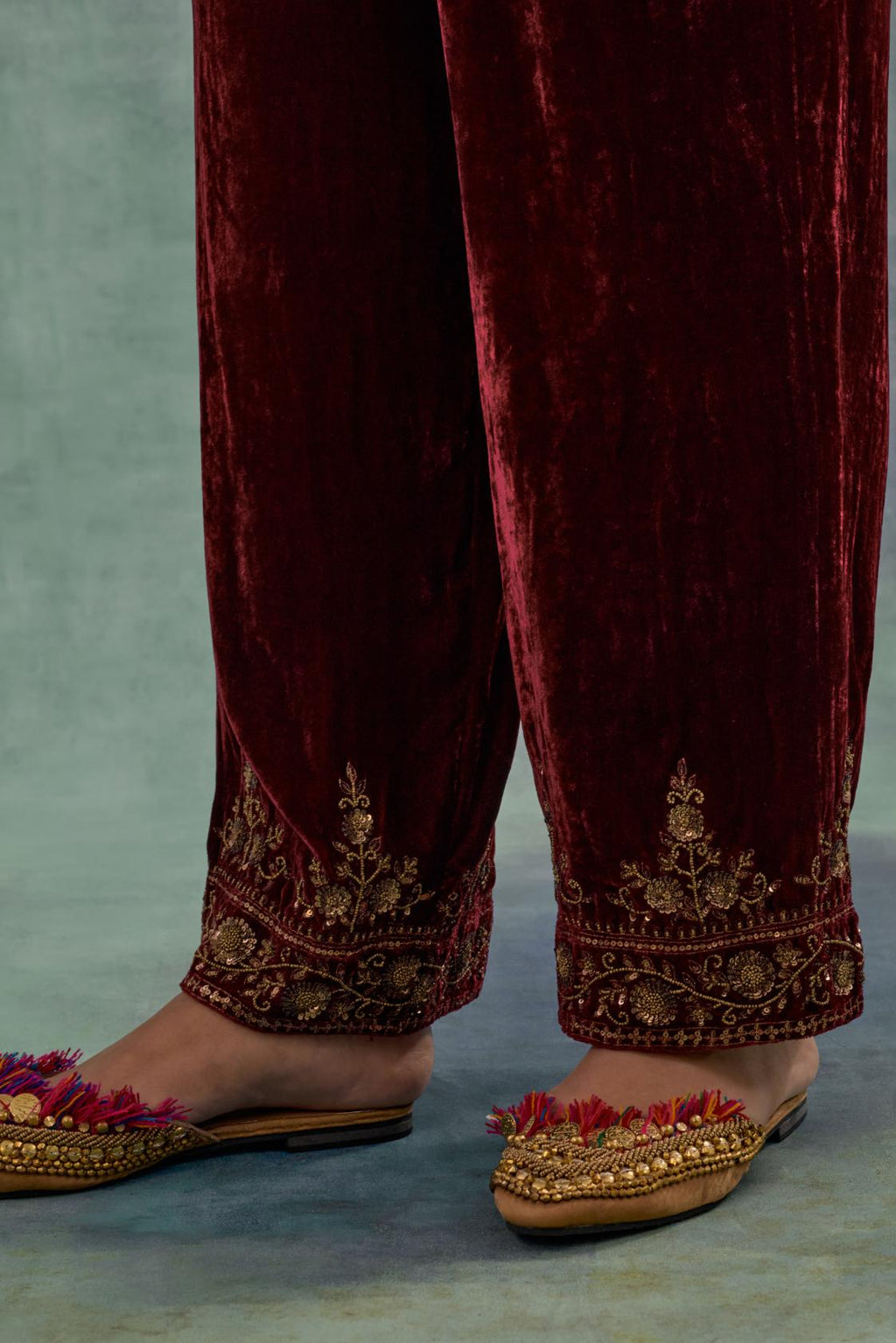 Deep maroon velvet straight pants. The hem is highlighted with hand-embroidered bead, sequins and zari motifs.