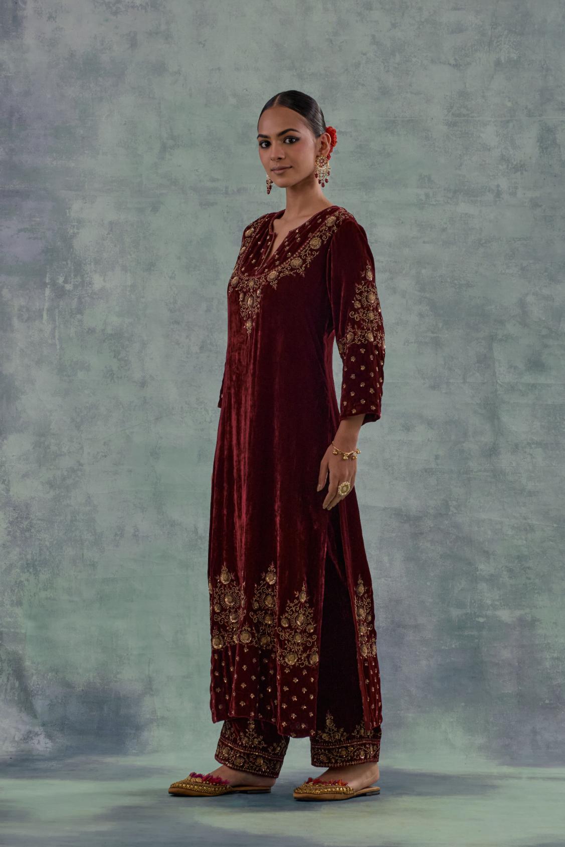 Deep maroon straight long kurta set in Silk Velvet with hand-embroidered bead, sequins and zari detailing on neck, sleeves and hem.