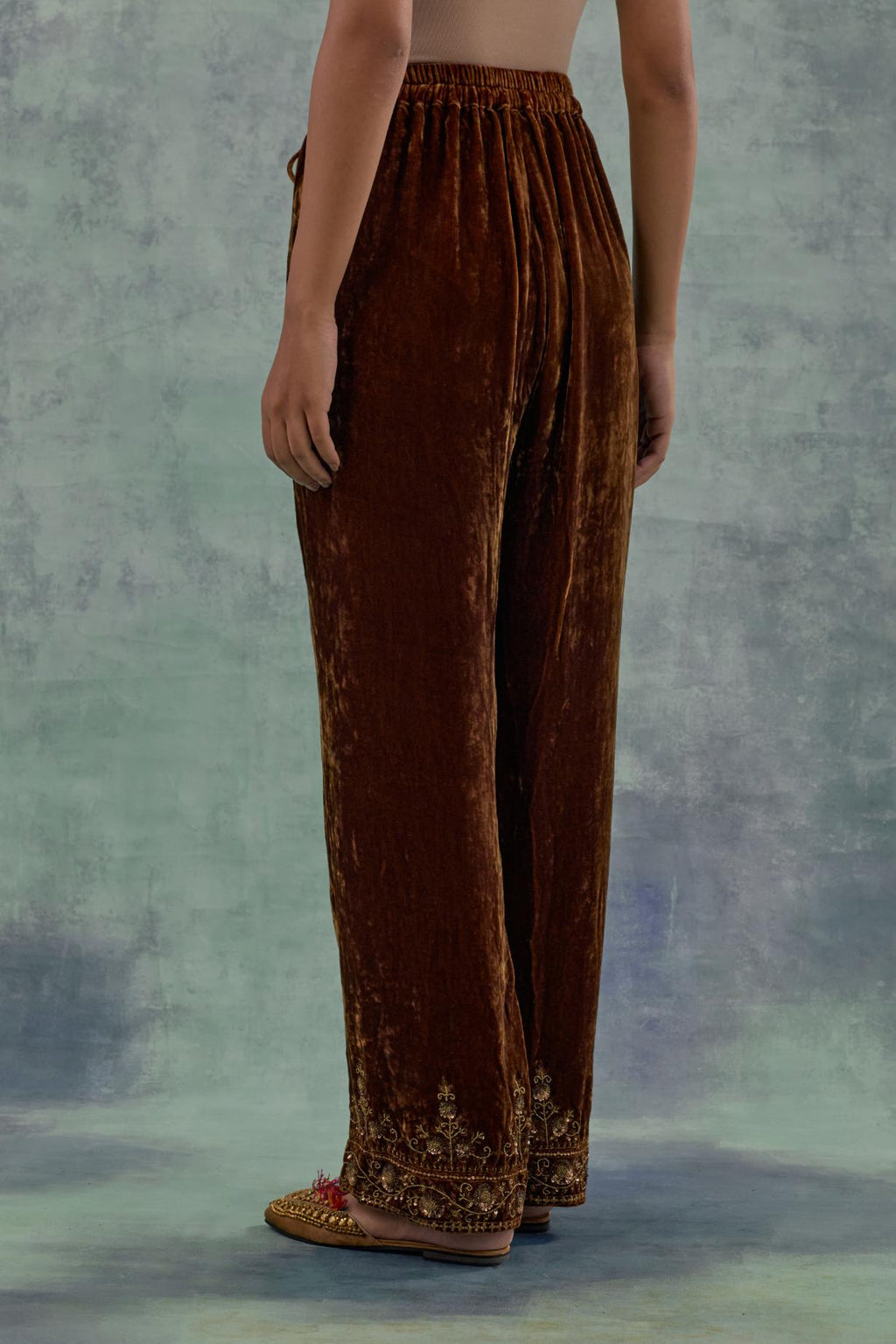 Russet velvet straight pants. The hem is highlighted with hand-embroidered bead, sequins and zari motifs.