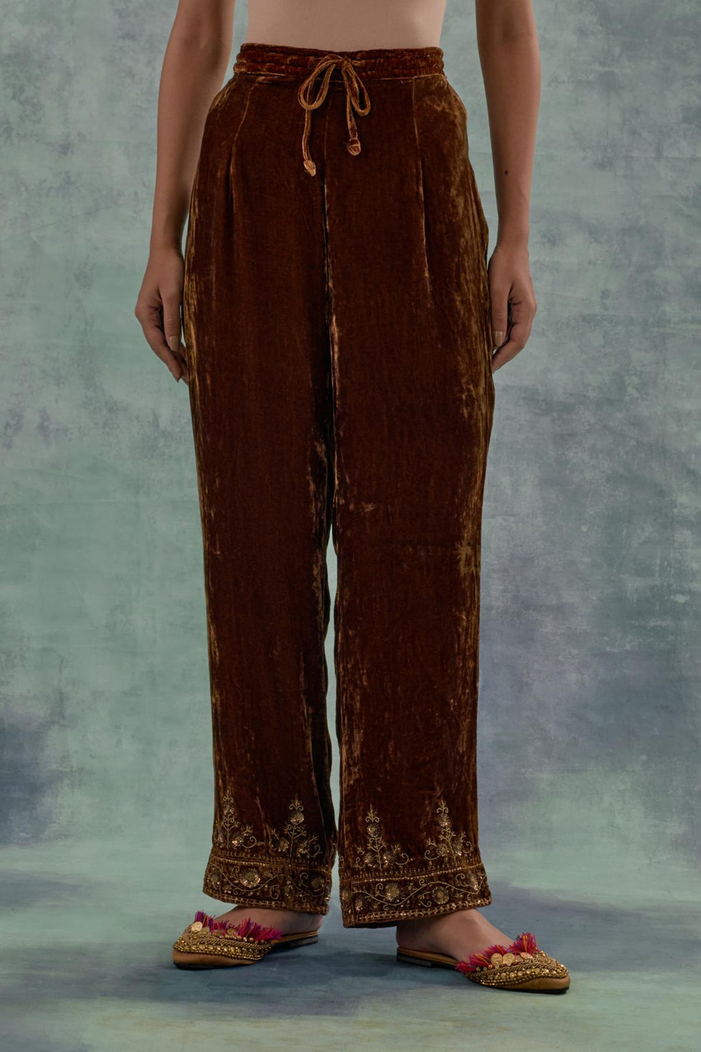 Russet velvet straight pants. The hem is highlighted with hand-embroidered bead, sequins and zari motifs.