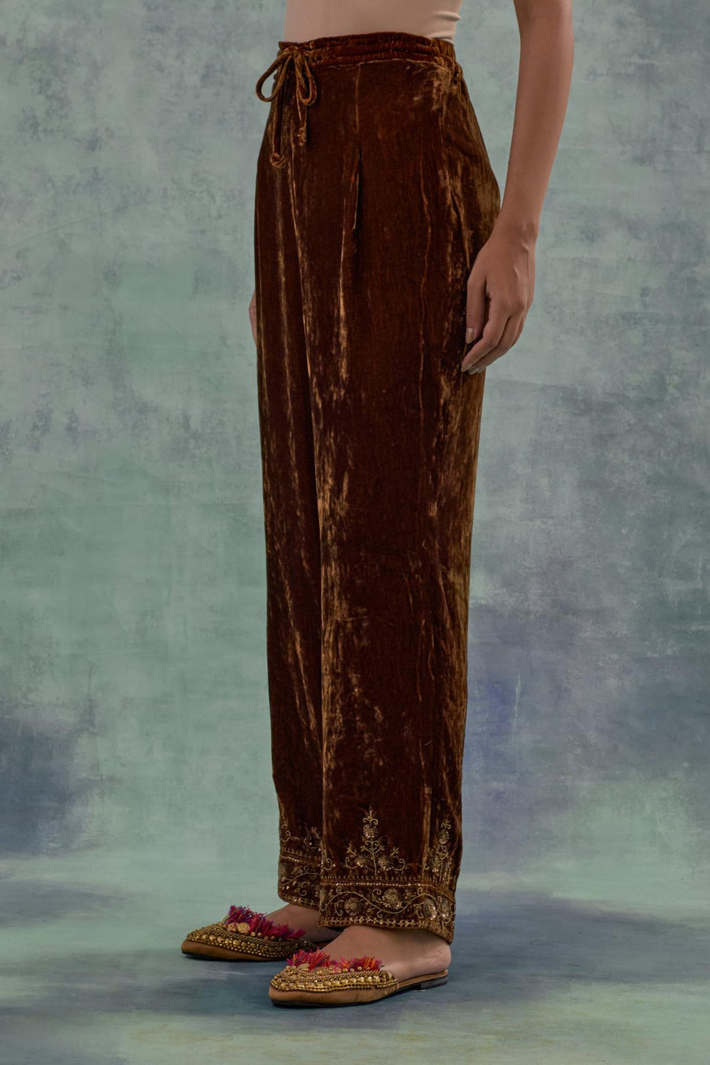 Russet velvet straight pants. The hem is highlighted with hand-embroidered bead, sequins and zari motifs.