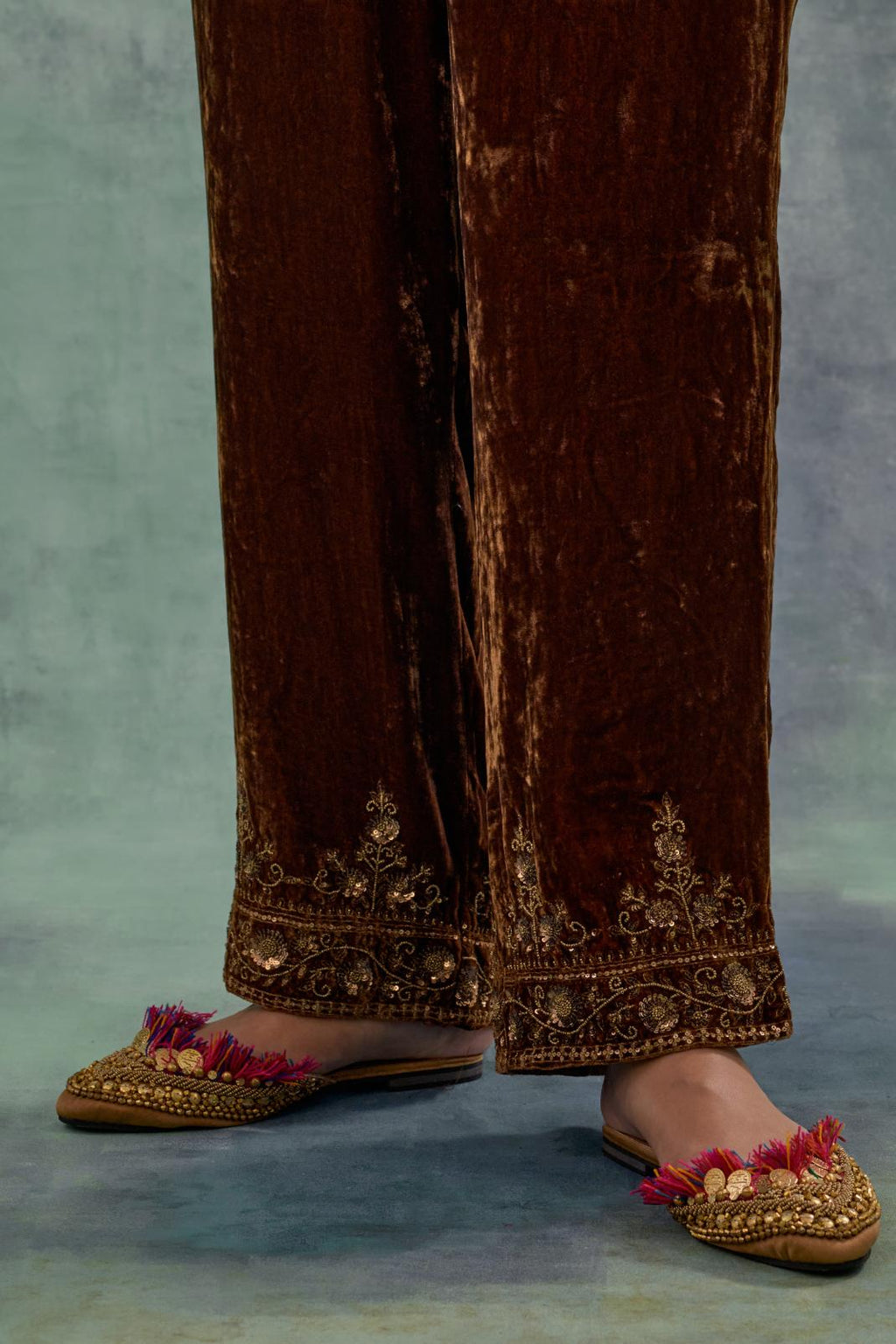 Russet velvet straight pants. The hem is highlighted with hand-embroidered bead, sequins and zari motifs.