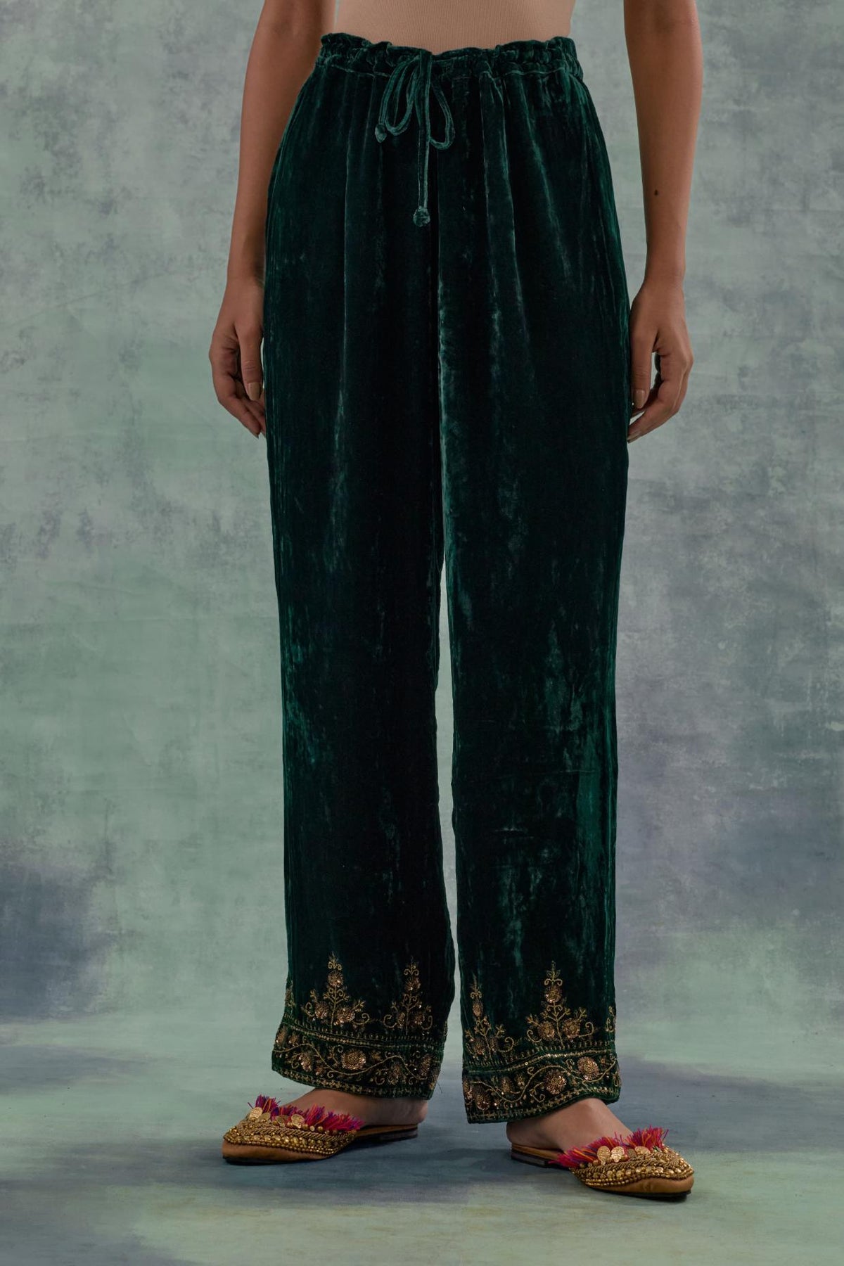 Emerald Green velvet straight pants. The hem is highlighted with hand-embroidered bead, sequins and zari motifs.