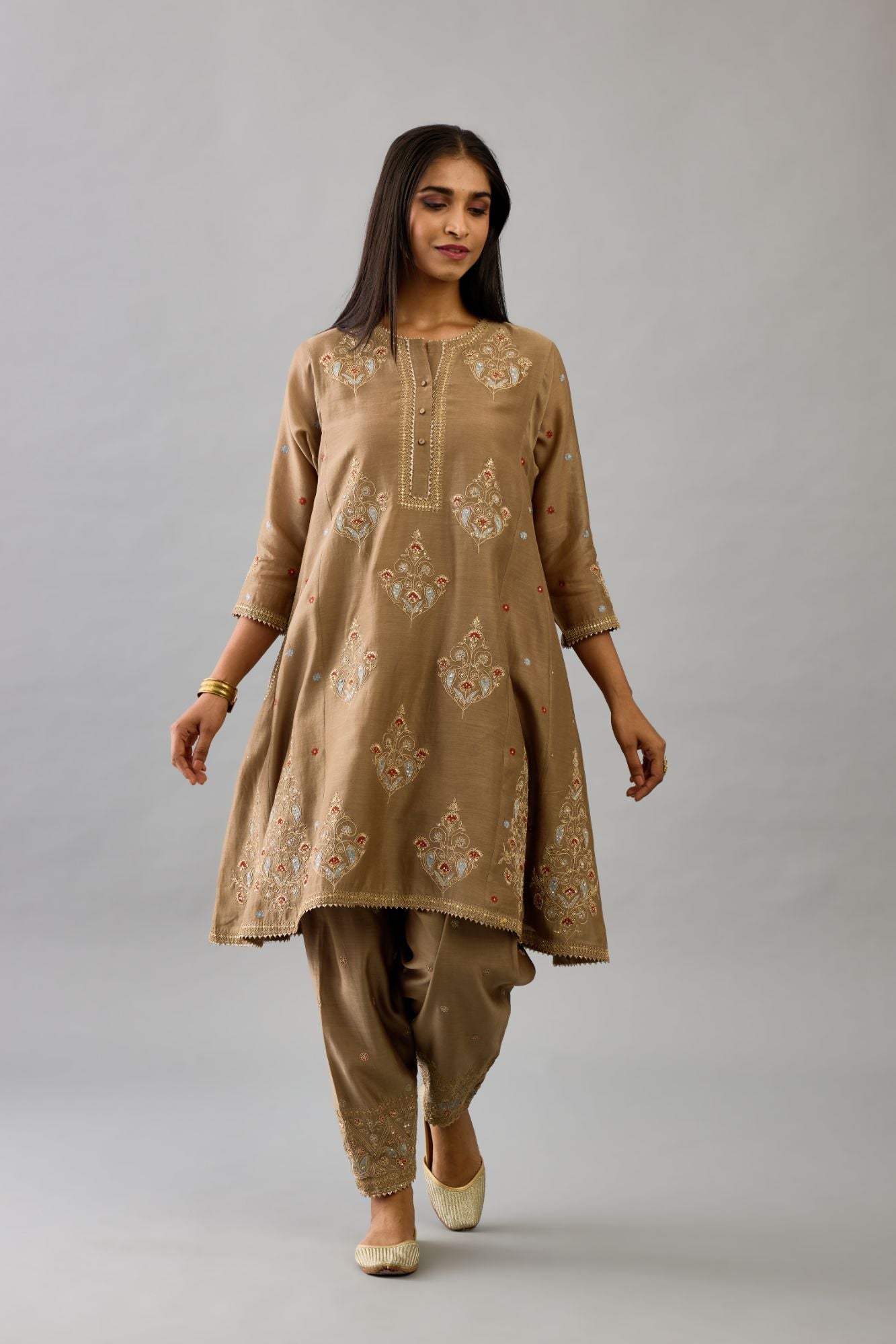 Taupe silk chanderi short kalidar phiran style kurta set with dori and contrast silk thread embroidery, highlighted with gold sequins work.