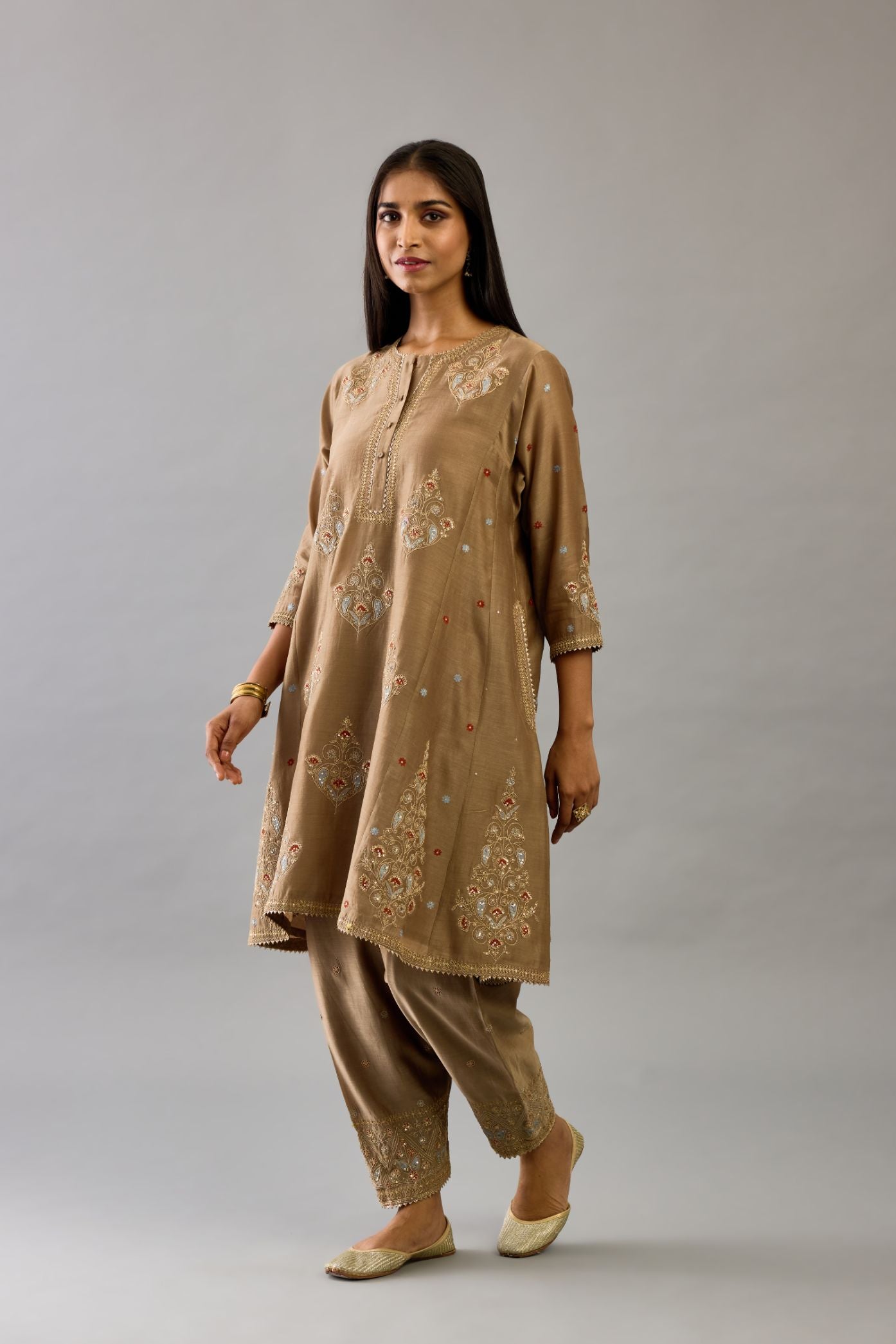 Taupe silk chanderi short kalidar phiran style kurta set with dori and contrast silk thread embroidery, highlighted with gold sequins work.