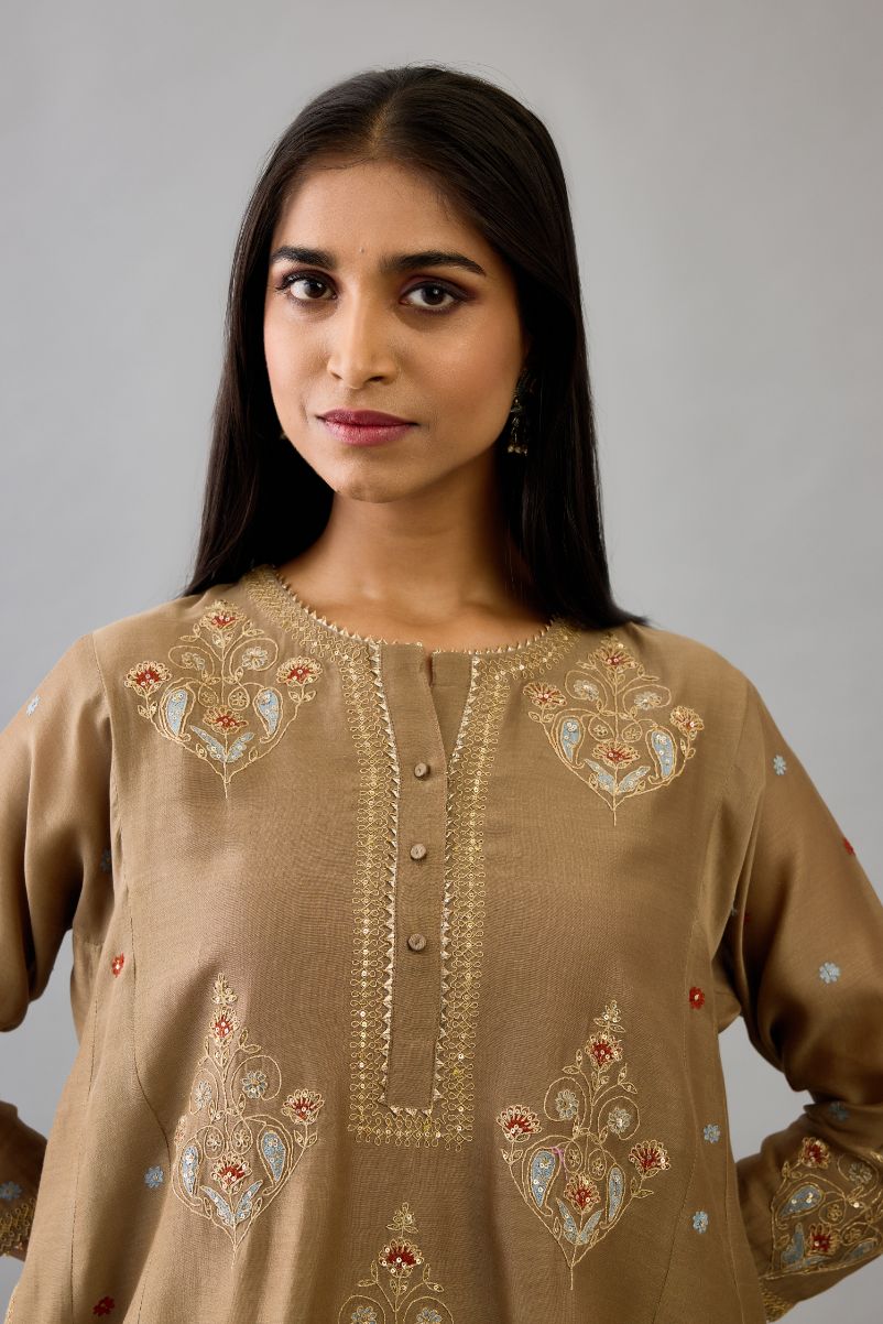 Taupe silk chanderi short kalidar phiran style kurta set with dori and contrast silk thread embroidery, highlighted with gold sequins work.