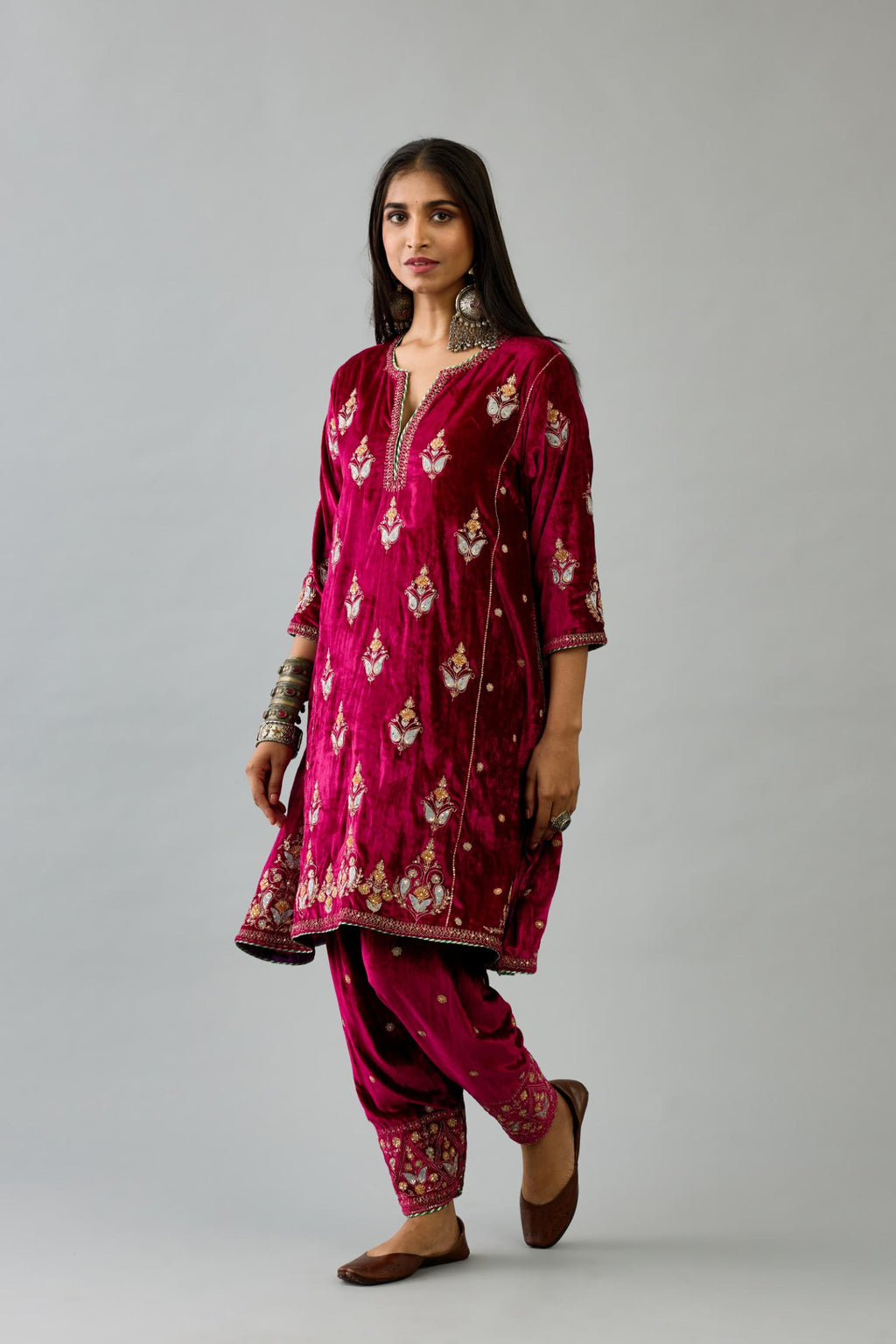 Fuchsia silk velvet A-line short kurta set with dori and contrast silk thread embroidery, highlighted with gold sequins work.