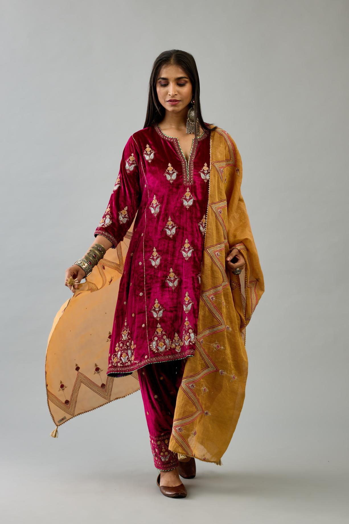 Fuchsia silk velvet A-line short kurta set with dori and contrast silk thread embroidery, highlighted with gold sequins work.