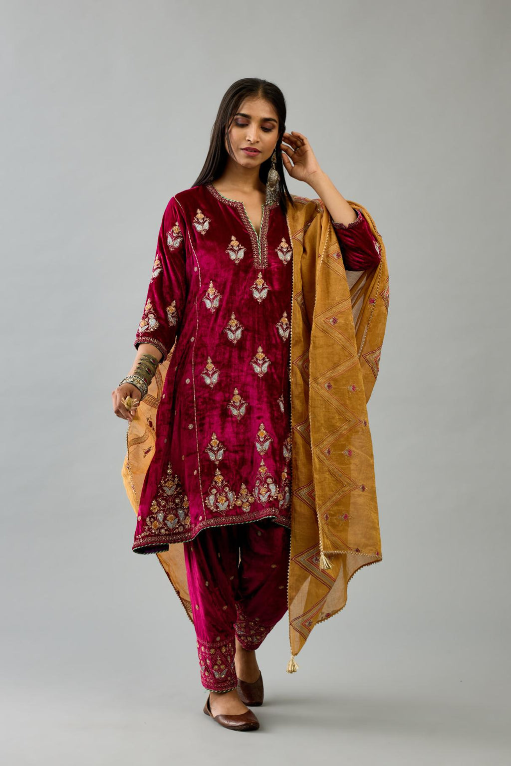 Fuchsia silk velvet A-line short kurta set with dori and contrast silk thread embroidery, highlighted with gold sequins work.