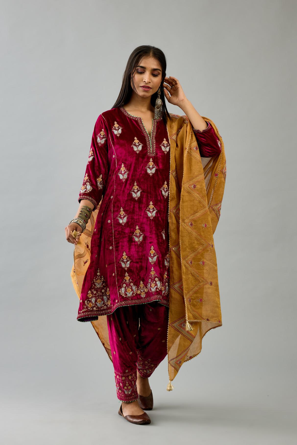 Fuchsia silk velvet A-line short kurta set with dori and contrast silk thread embroidery, highlighted with gold sequins work.