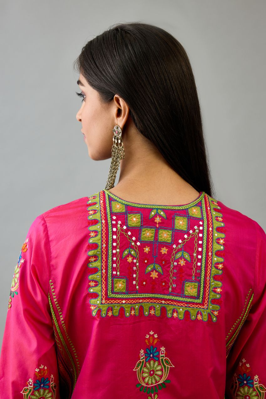 Fuchsia silk straight kurta set with yoke and side panels. It has allover patchwork and silk thread embroidery, highlighted with mirror, sequins, tassels and braids.