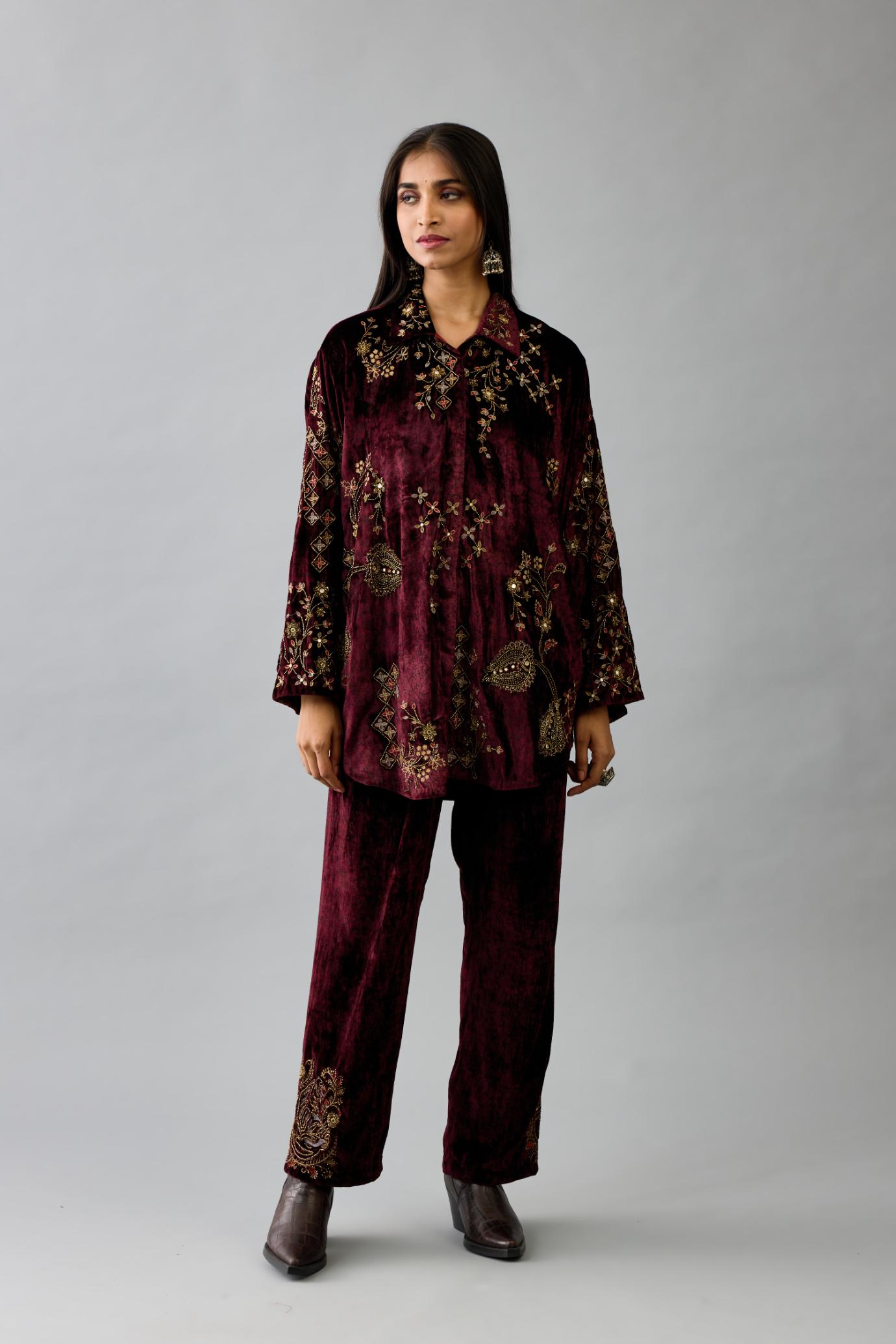 Maroon silk velvet shirt with all-over hand block print, highlighted with sequins, beads and zari work, paired with maroon silk velvet hand block printed straight pants with embroidered boota at sides, highlighted with sequins, beads and zari work.