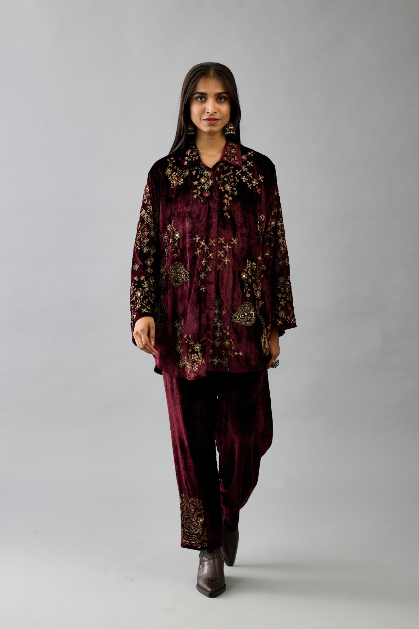 Maroon silk velvet shirt with all-over hand block print, highlighted with sequins, beads and zari work, paired with maroon silk velvet hand block printed straight pants with embroidered boota at sides, highlighted with sequins, beads and zari work.