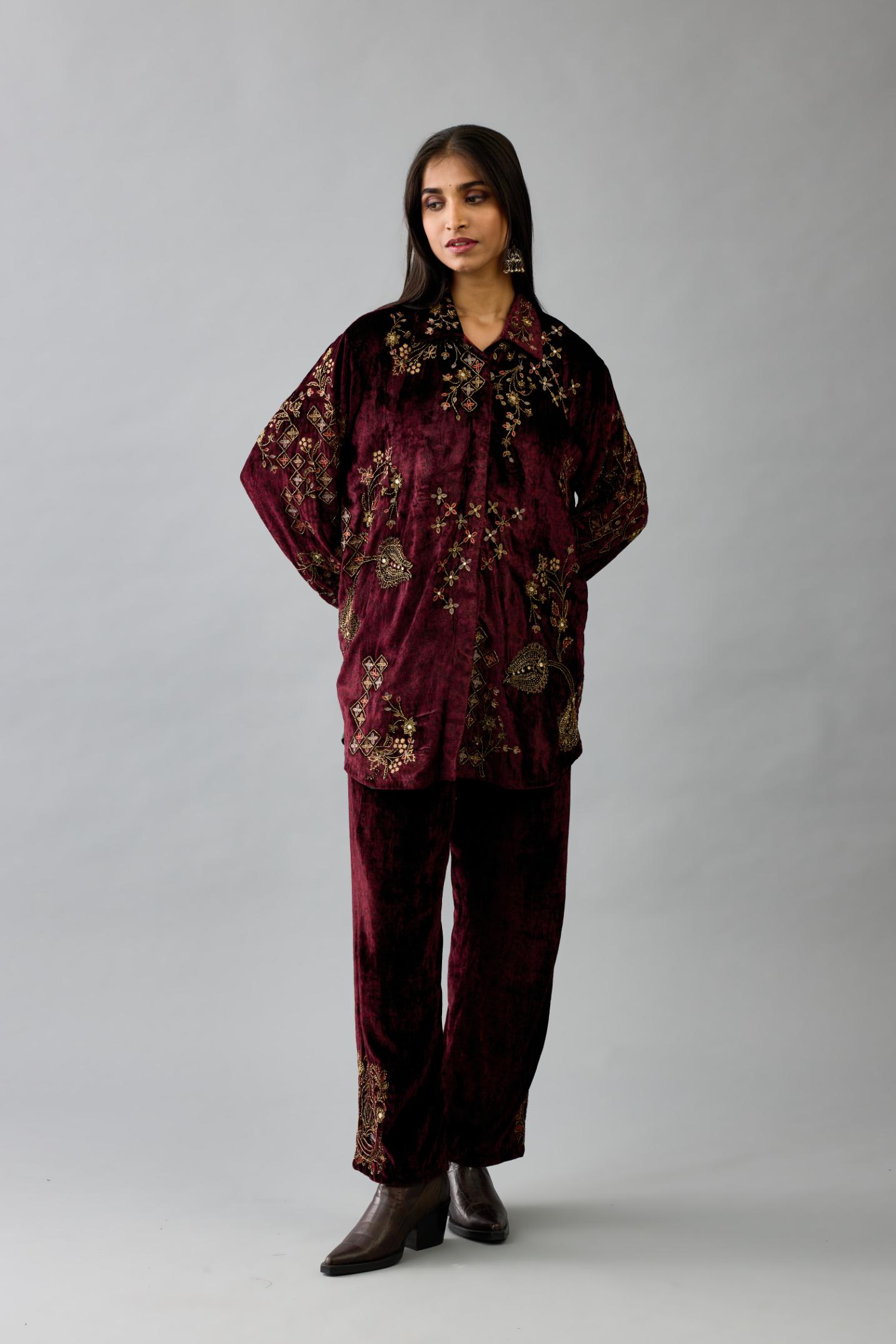 Maroon silk velvet shirt with all-over hand block print, highlighted with sequins, beads and zari work, paired with maroon silk velvet hand block printed straight pants with embroidered boota at sides, highlighted with sequins, beads and zari work.