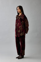 Maroon silk velvet shirt with all-over hand block print, highlighted with sequins, beads and zari work, paired with maroon silk velvet hand block printed straight pants with embroidered boota at sides, highlighted with sequins, beads and zari work.