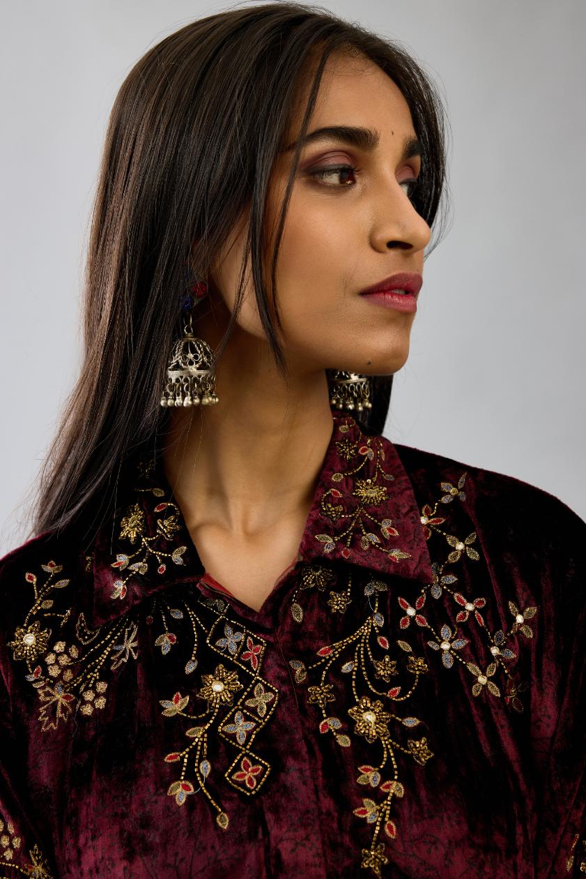 Maroon silk velvet shirt with all-over hand block print, highlighted with sequins, beads and zari work, paired with maroon silk velvet hand block printed straight pants with embroidered boota at sides, highlighted with sequins, beads and zari work.
