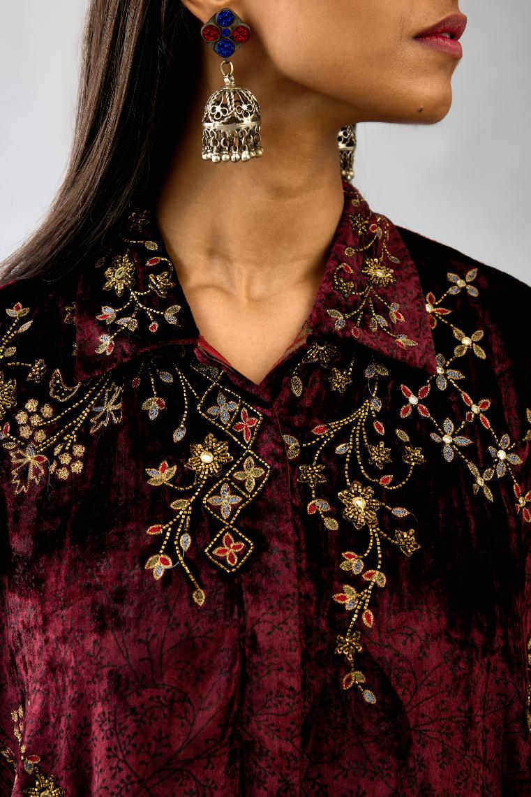Maroon silk velvet shirt with all-over hand block print, highlighted with sequins, beads and zari work, paired with maroon silk velvet hand block printed straight pants with embroidered boota at sides, highlighted with sequins, beads and zari work.