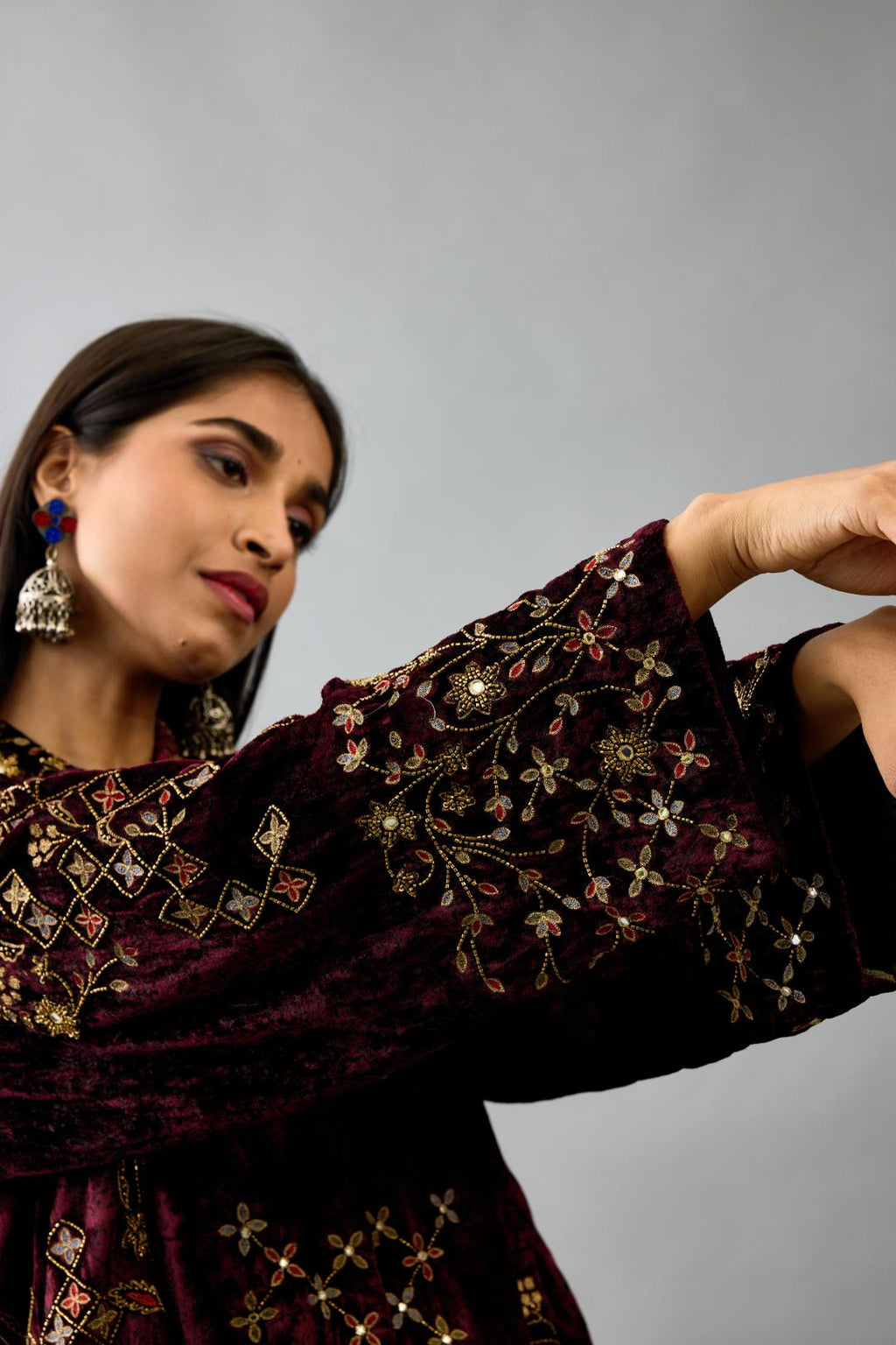 Maroon silk velvet shirt with all-over hand block print, highlighted with sequins, beads and zari work, paired with maroon silk velvet hand block printed straight pants with embroidered boota at sides, highlighted with sequins, beads and zari work.