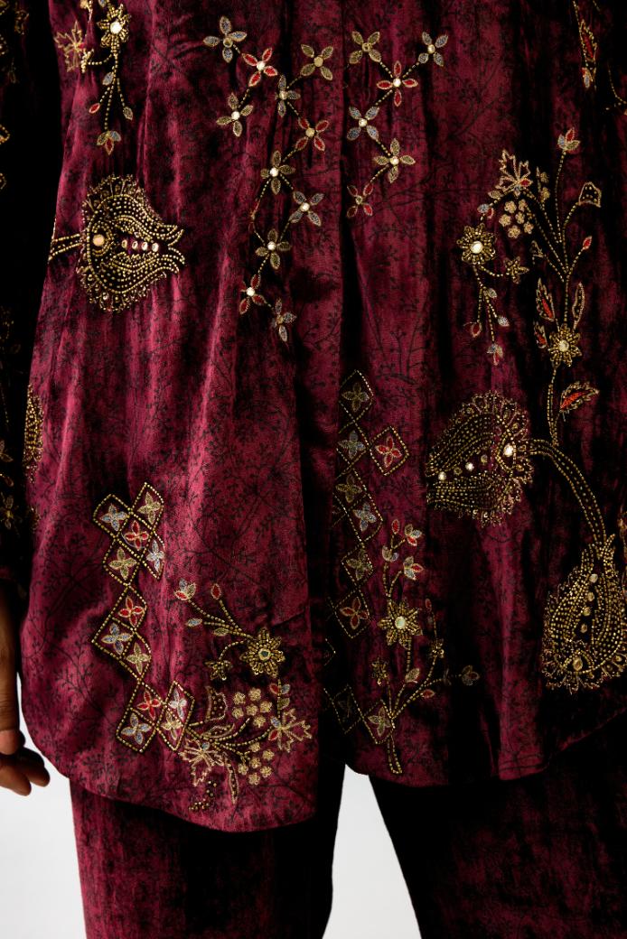 Maroon silk velvet shirt with all-over hand block print, highlighted with sequins, beads and zari work, paired with maroon silk velvet hand block printed straight pants with embroidered boota at sides, highlighted with sequins, beads and zari work.
