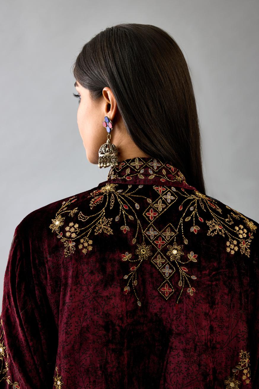 Maroon silk velvet shirt with all-over hand block print, highlighted with sequins, beads and zari work, paired with maroon silk velvet hand block printed straight pants with embroidered boota at sides, highlighted with sequins, beads and zari work.