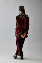 Maroon silk velvet shirt with all-over hand block print, highlighted with sequins, beads and zari work, paired with maroon silk velvet hand block printed straight pants with embroidered boota at sides, highlighted with sequins, beads and zari work.