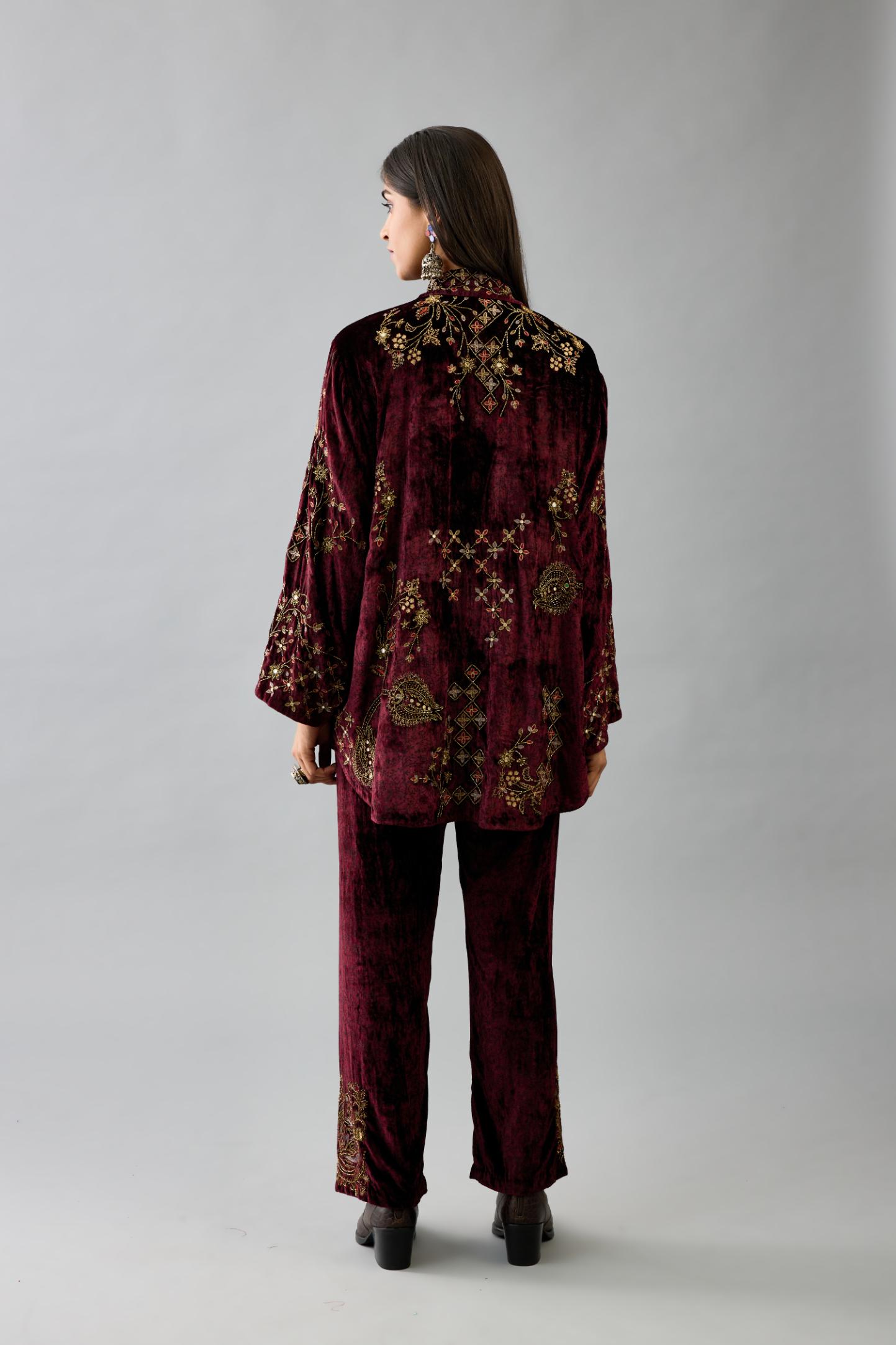 Maroon silk velvet shirt with all-over hand block print, highlighted with sequins, beads and zari work, paired with maroon silk velvet hand block printed straight pants with embroidered boota at sides, highlighted with sequins, beads and zari work.