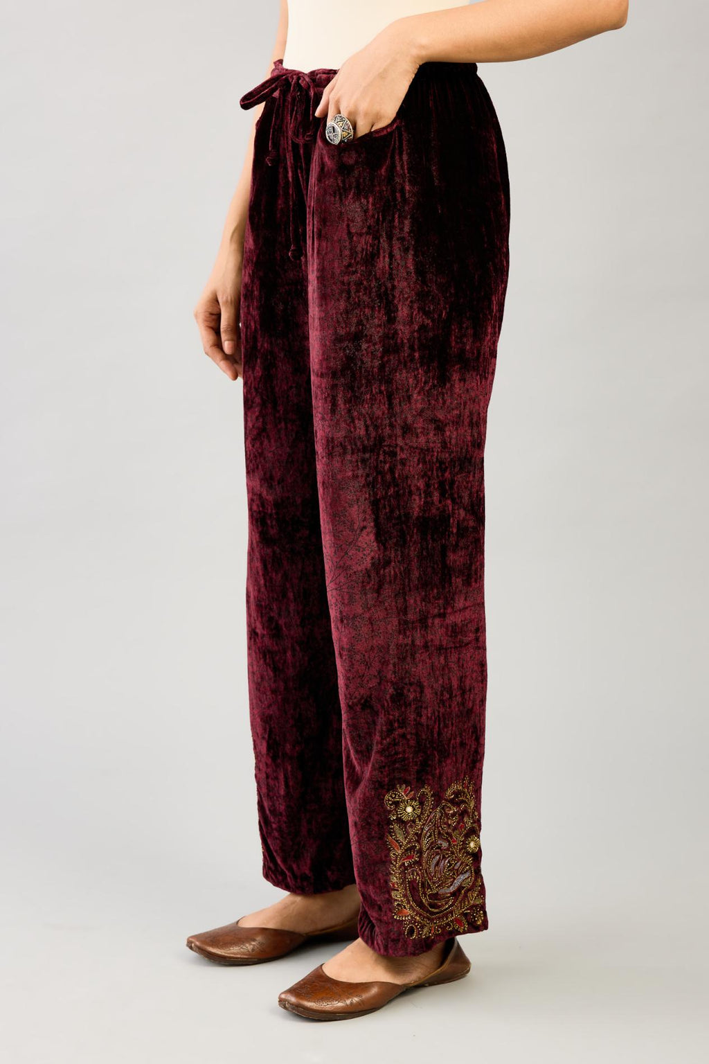 Maroon silk velvet hand block printed straight pants with embroidered boota at sides, highlighted with sequins, beads and zari work.