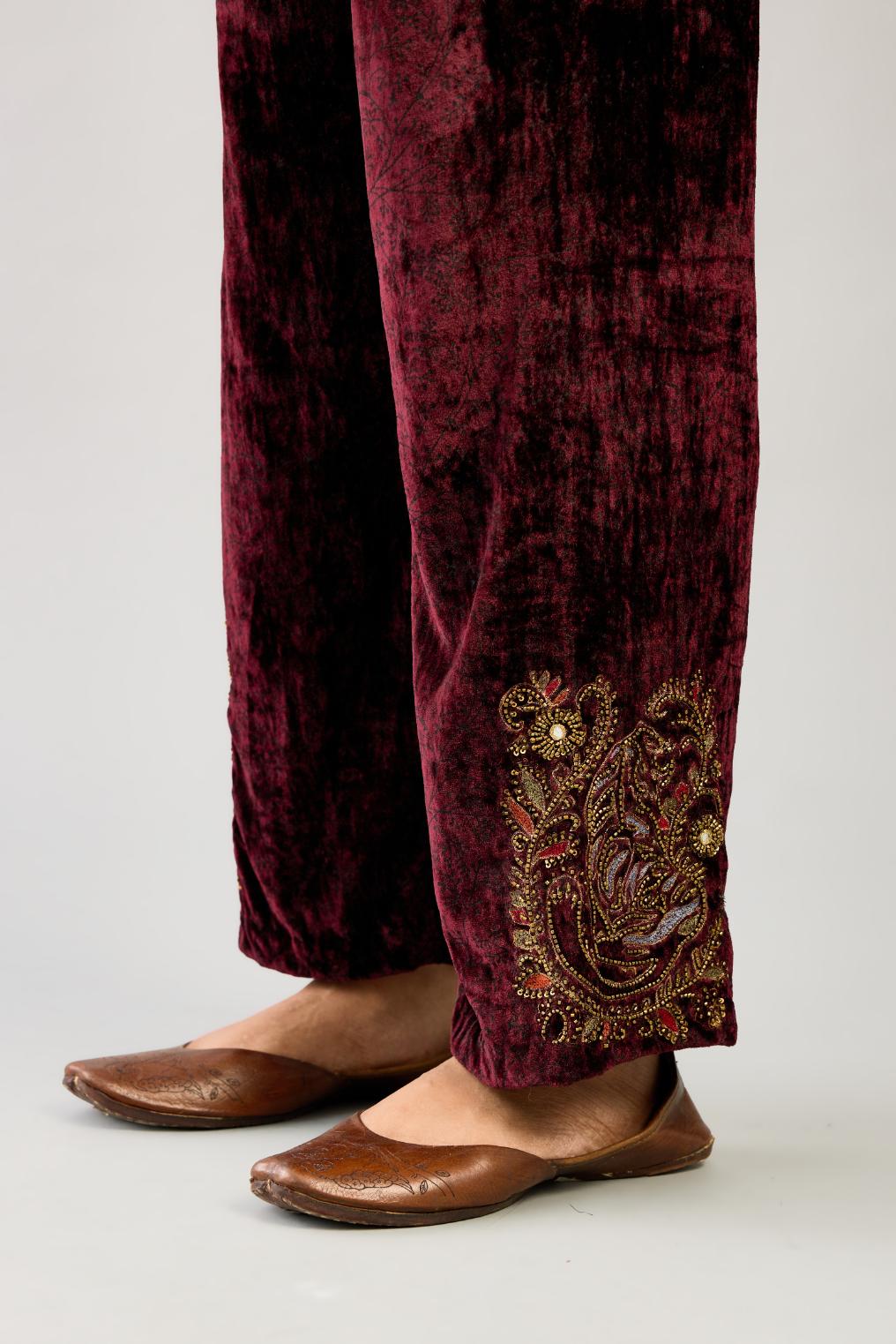 Maroon silk velvet hand block printed straight pants with embroidered boota at sides, highlighted with sequins, beads and zari work.