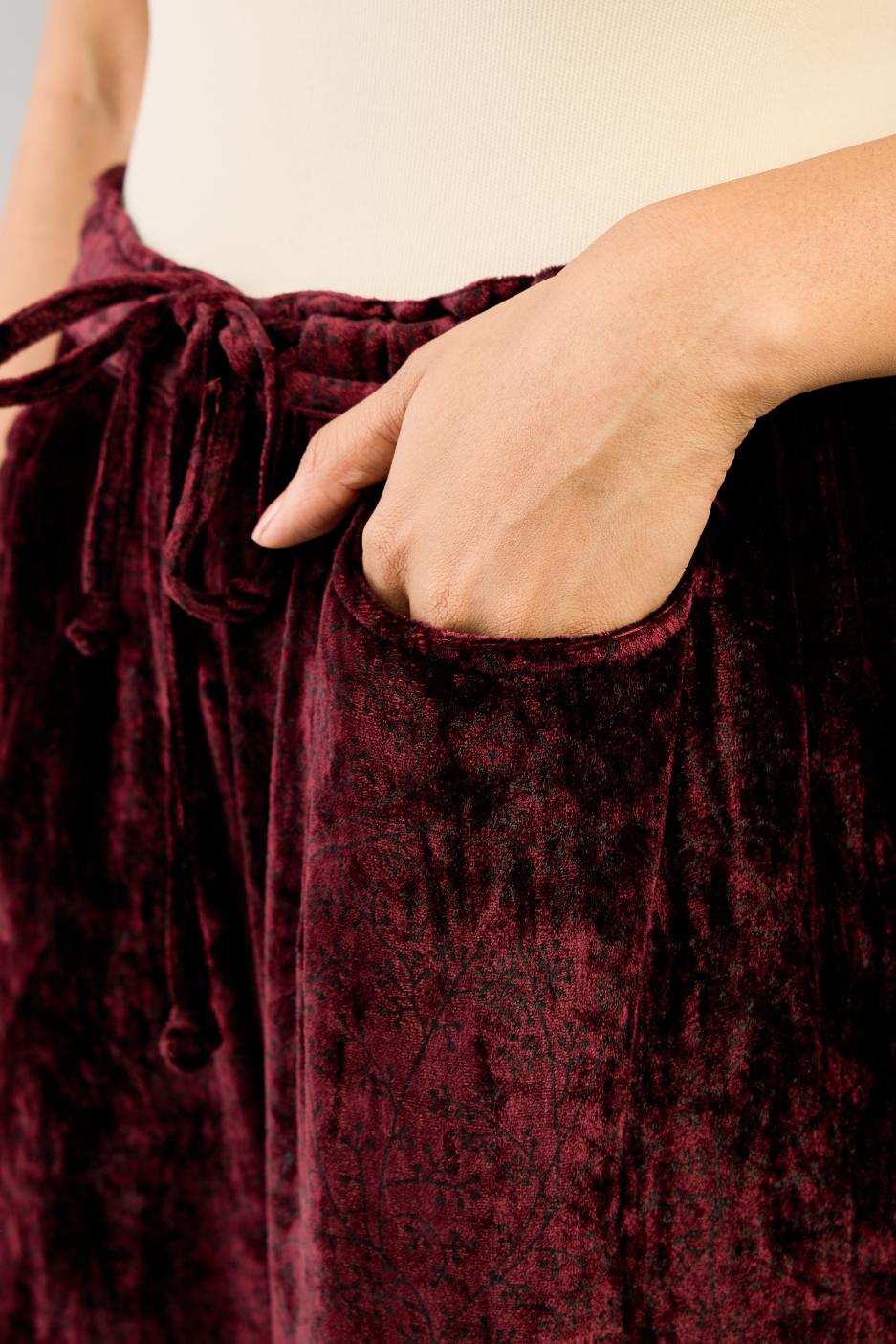 Maroon silk velvet hand block printed straight pants with embroidered boota at sides, highlighted with sequins, beads and zari work.