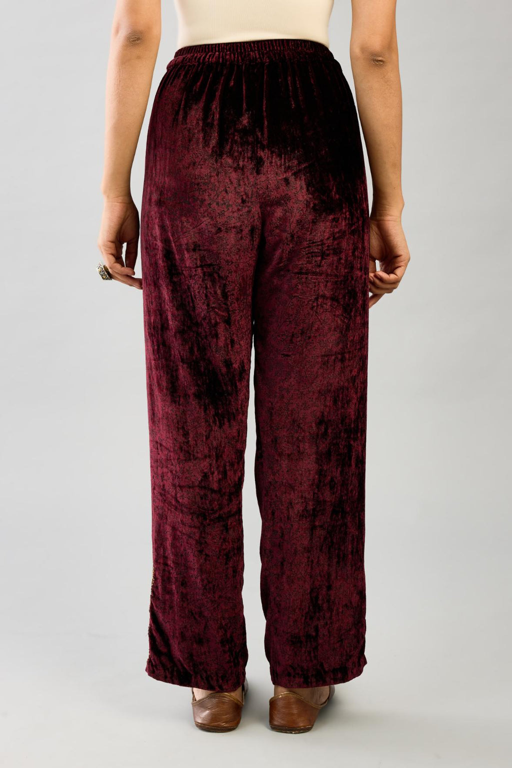 Maroon silk velvet hand block printed straight pants with embroidered boota at sides, highlighted with sequins, beads and zari work.