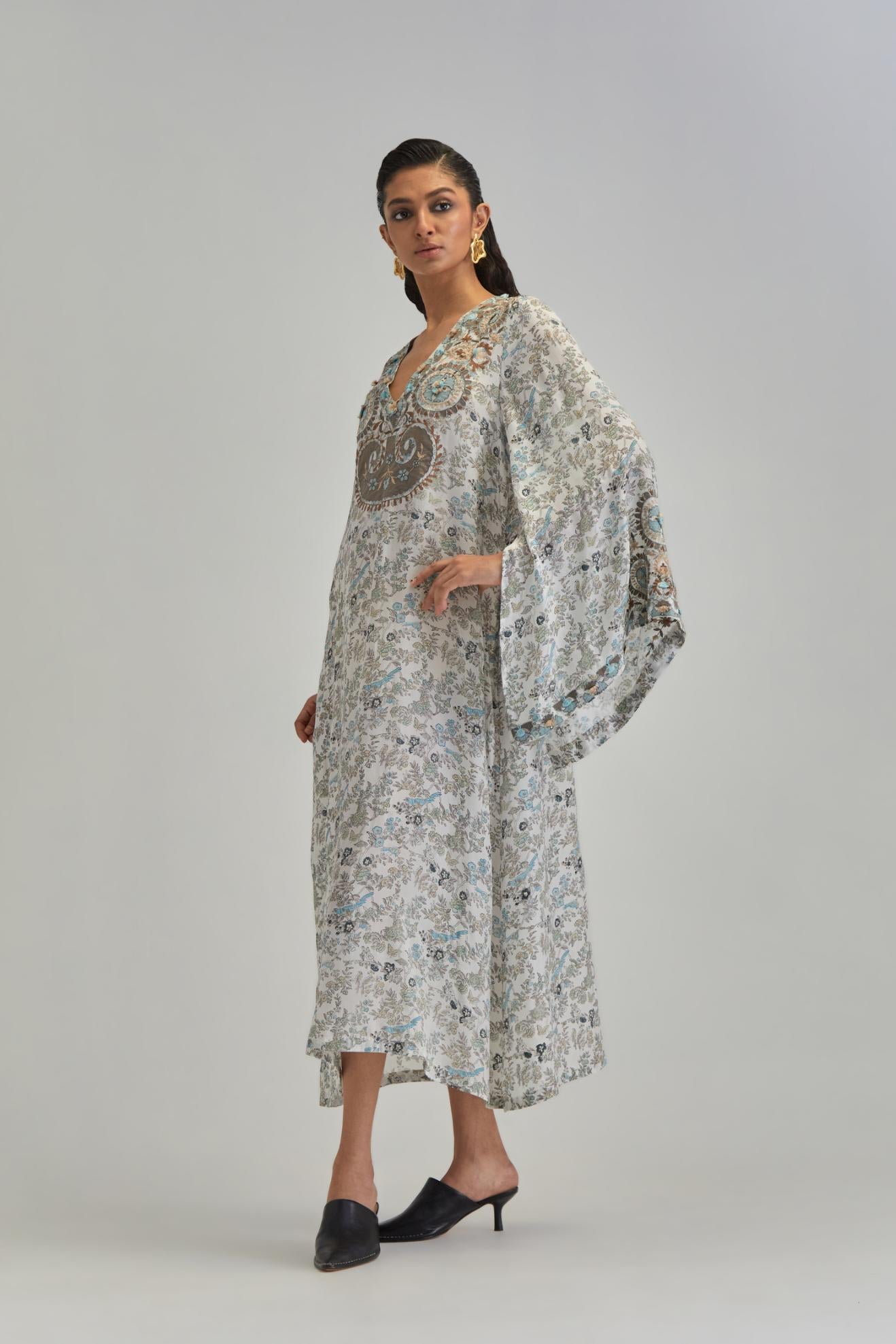 Off White long A-line kaftan with all-over earthy coloured hand block print and appliqué flowers, thread work and silk tassels.