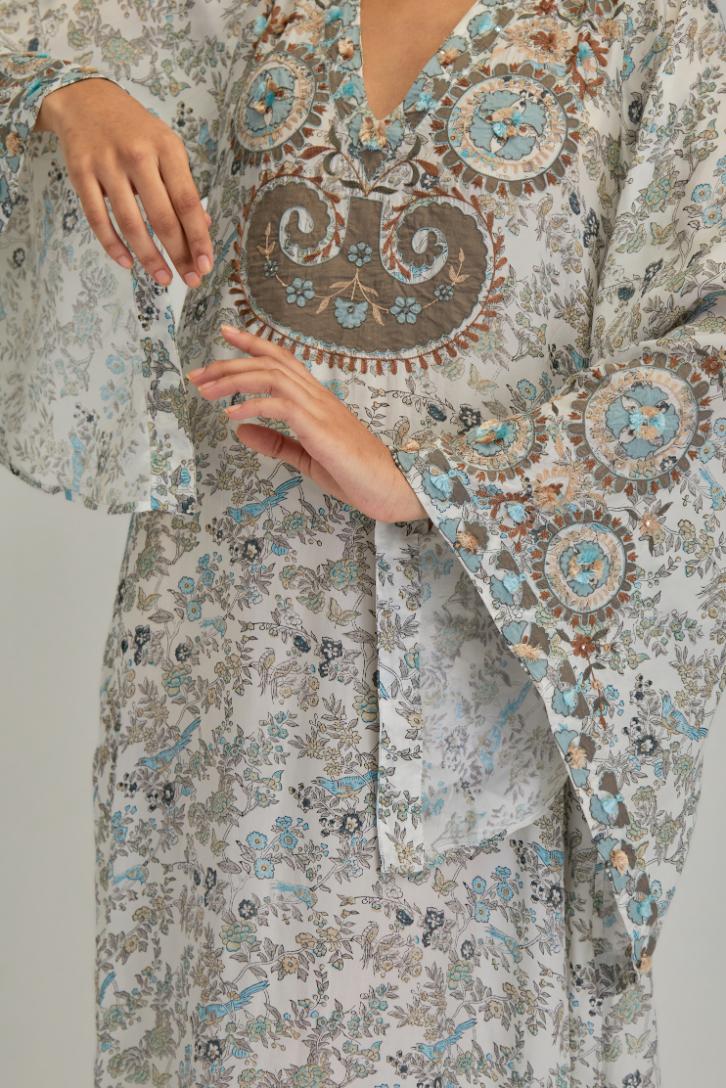 Off White long A-line kaftan with all-over earthy coloured hand block print and appliqué flowers, thread work and silk tassels.