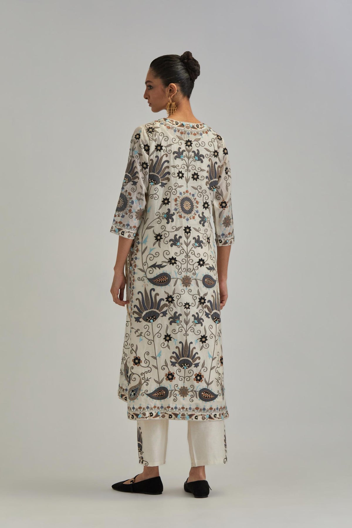 Off White straight kurta set, fully embroidered with bold appliqué flowers, earthy-coloured Aari thread work and silk tassels.