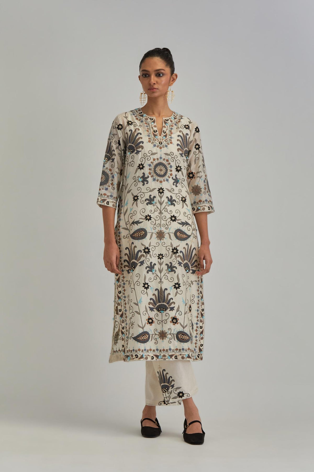 Off White straight kurta set, fully embroidered with bold appliqué flowers, earthy-coloured Aari thread work and silk tassels.