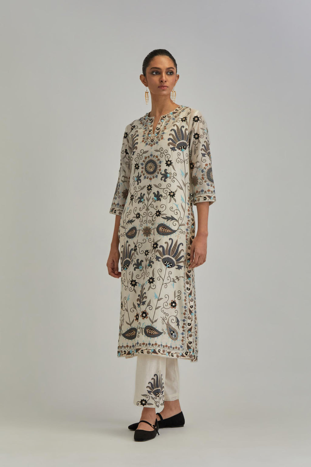 Off White straight kurta set, fully embroidered with bold appliqué flowers, earthy-coloured Aari thread work and silk tassels.