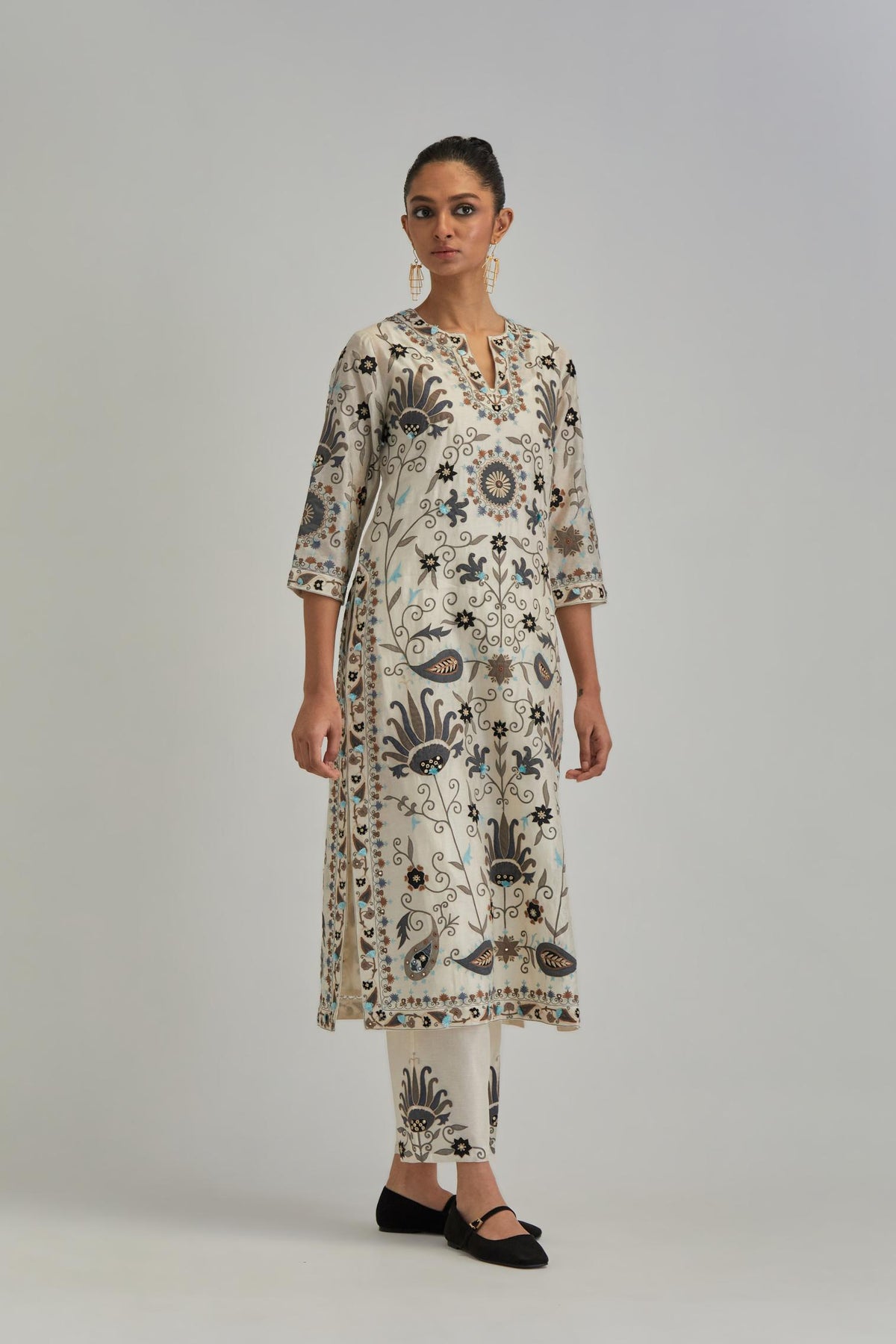 Off White straight kurta set, fully embroidered with bold appliqué flowers, earthy-coloured Aari thread work and silk tassels.
