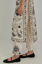 Off White straight kurta set, fully embroidered with bold appliqué flowers, earthy-coloured Aari thread work and silk tassels.