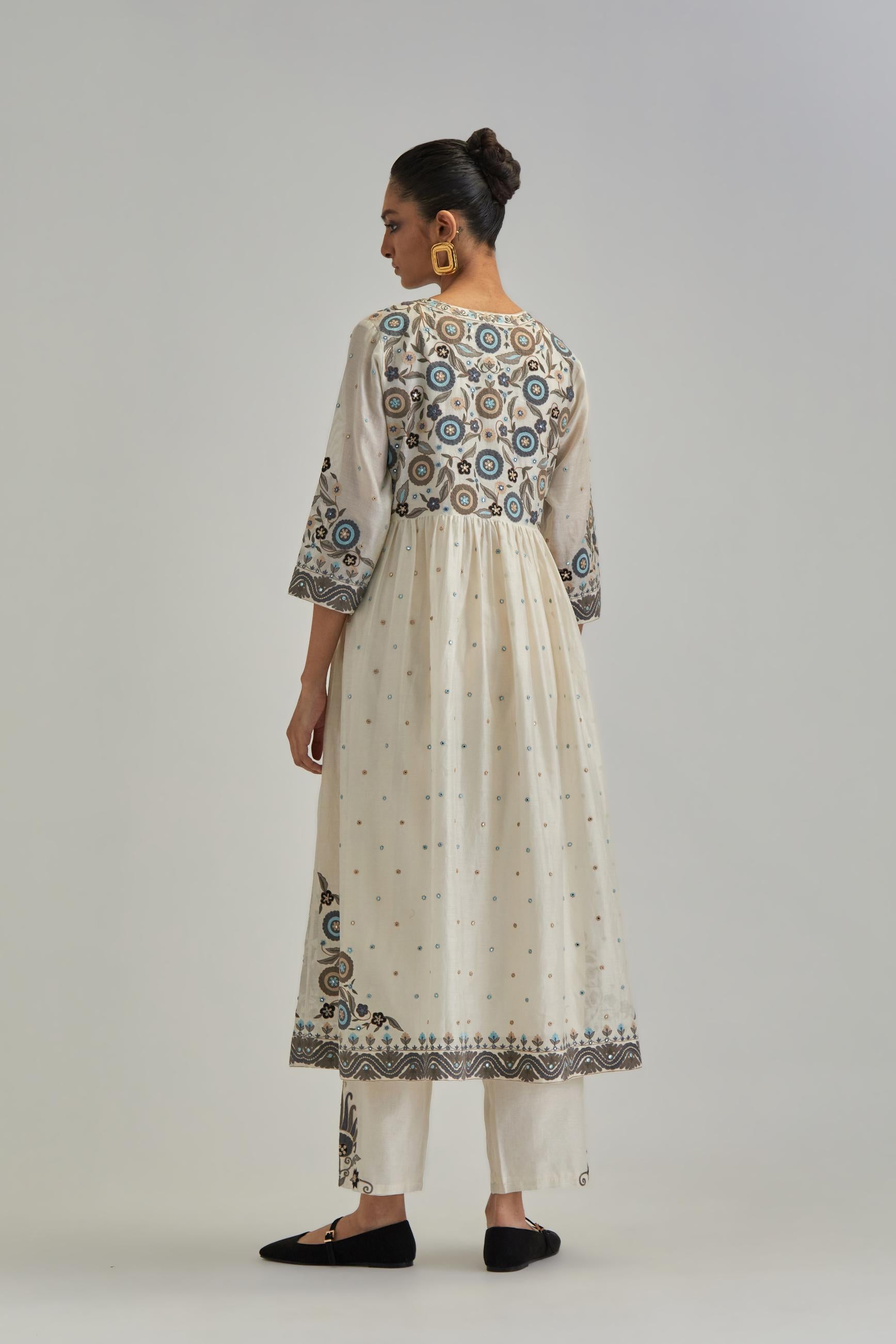 Off White silk Chanderi kurta-dress set with a wavy high-waist and fine gathers. The yoke is fully embroidered with earthy coloured circular appliqué and Aari thread work.