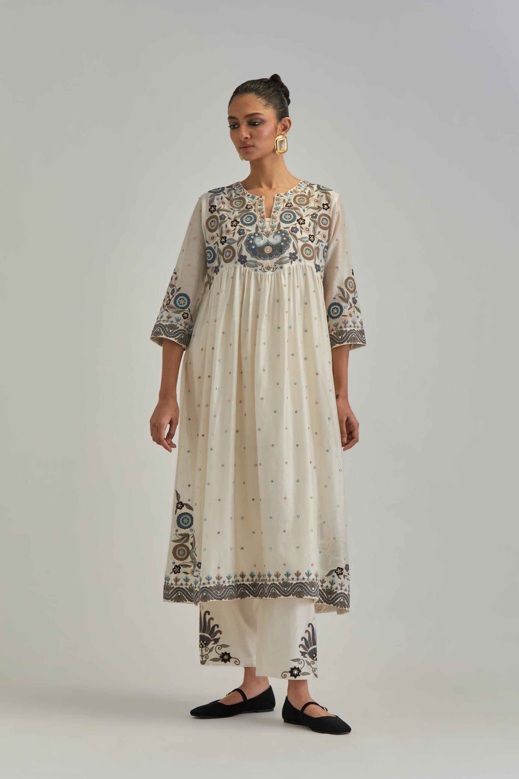 Off White silk Chanderi kurta-dress set with a wavy high-waist and fine gathers. The yoke is fully embroidered with earthy coloured circular appliqué and Aari thread work.