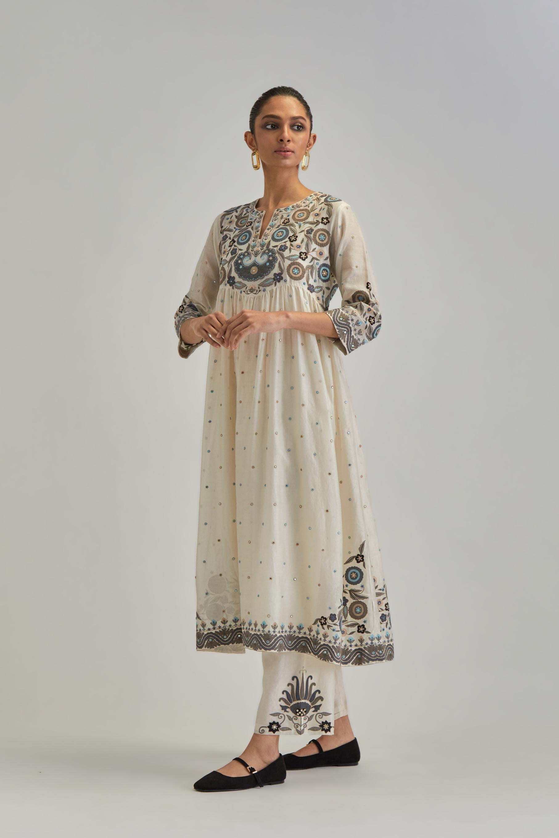 Off White silk Chanderi kurta-dress set with a wavy high-waist and fine gathers. The yoke is fully embroidered with earthy coloured circular appliqué and Aari thread work.