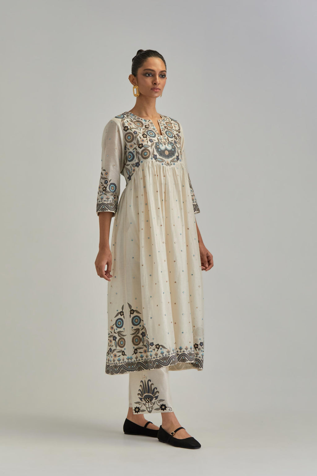 Off White silk Chanderi kurta-dress set with a wavy high-waist and fine gathers. The yoke is fully embroidered with earthy coloured circular appliqué and Aari thread work.
