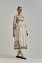 Off White silk Chanderi kurta-dress set with a wavy high-waist and fine gathers. The yoke is fully embroidered with earthy coloured circular appliqué and Aari thread work.