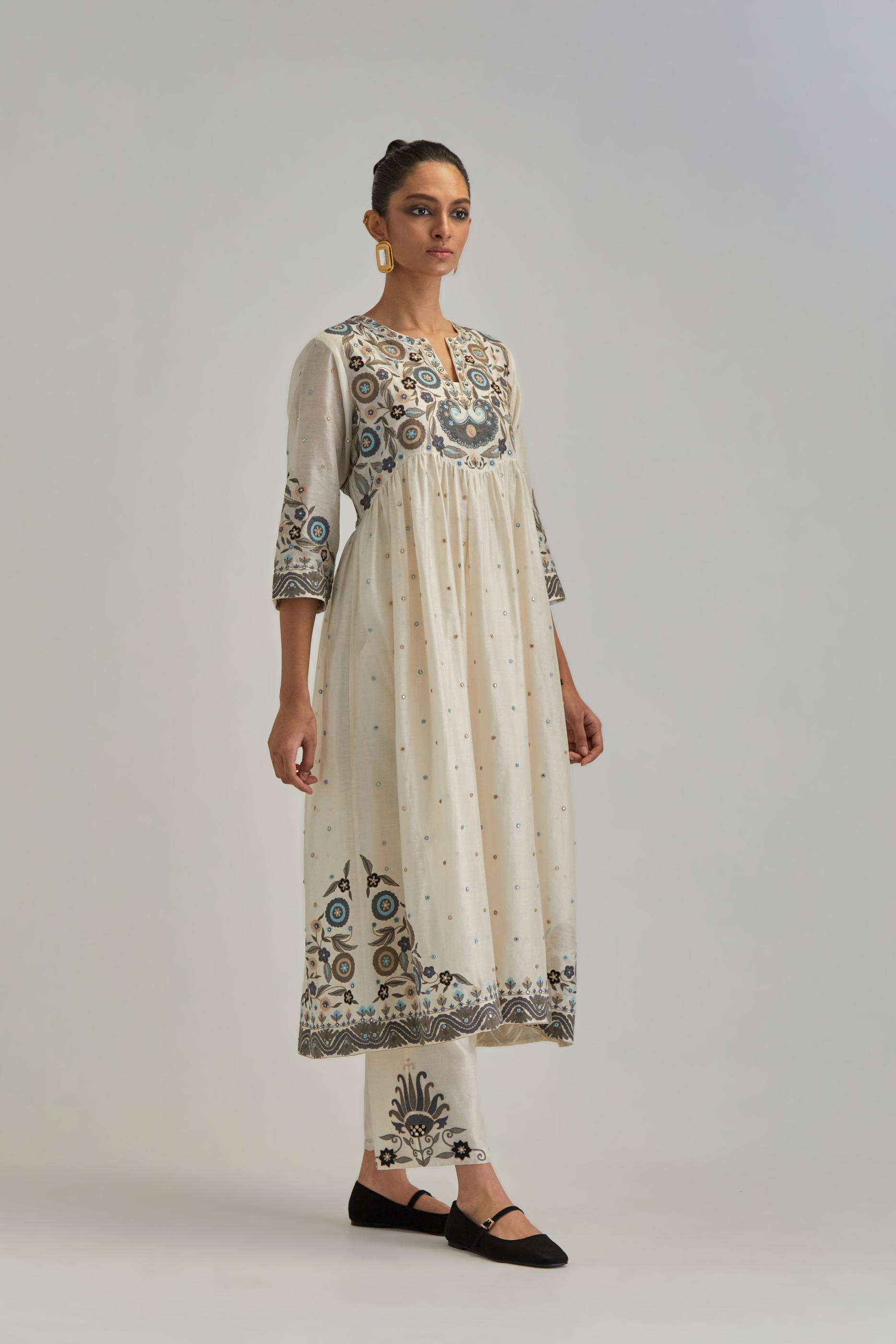 Off White silk Chanderi kurta-dress set with a wavy high-waist and fine gathers. The yoke is fully embroidered with earthy coloured circular appliqué and Aari thread work.