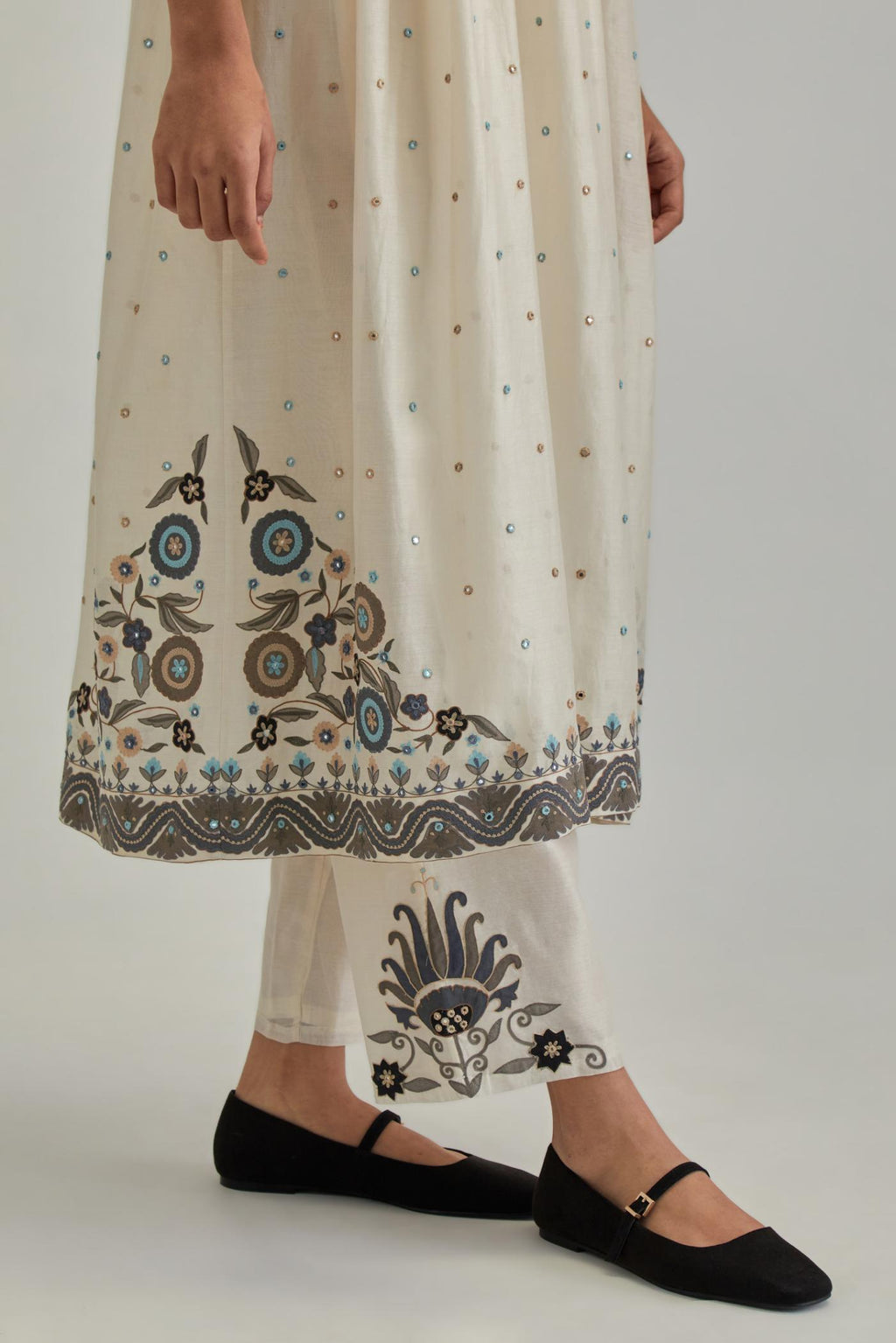 Off White silk Chanderi kurta-dress set with a wavy high-waist and fine gathers. The yoke is fully embroidered with earthy coloured circular appliqué and Aari thread work.