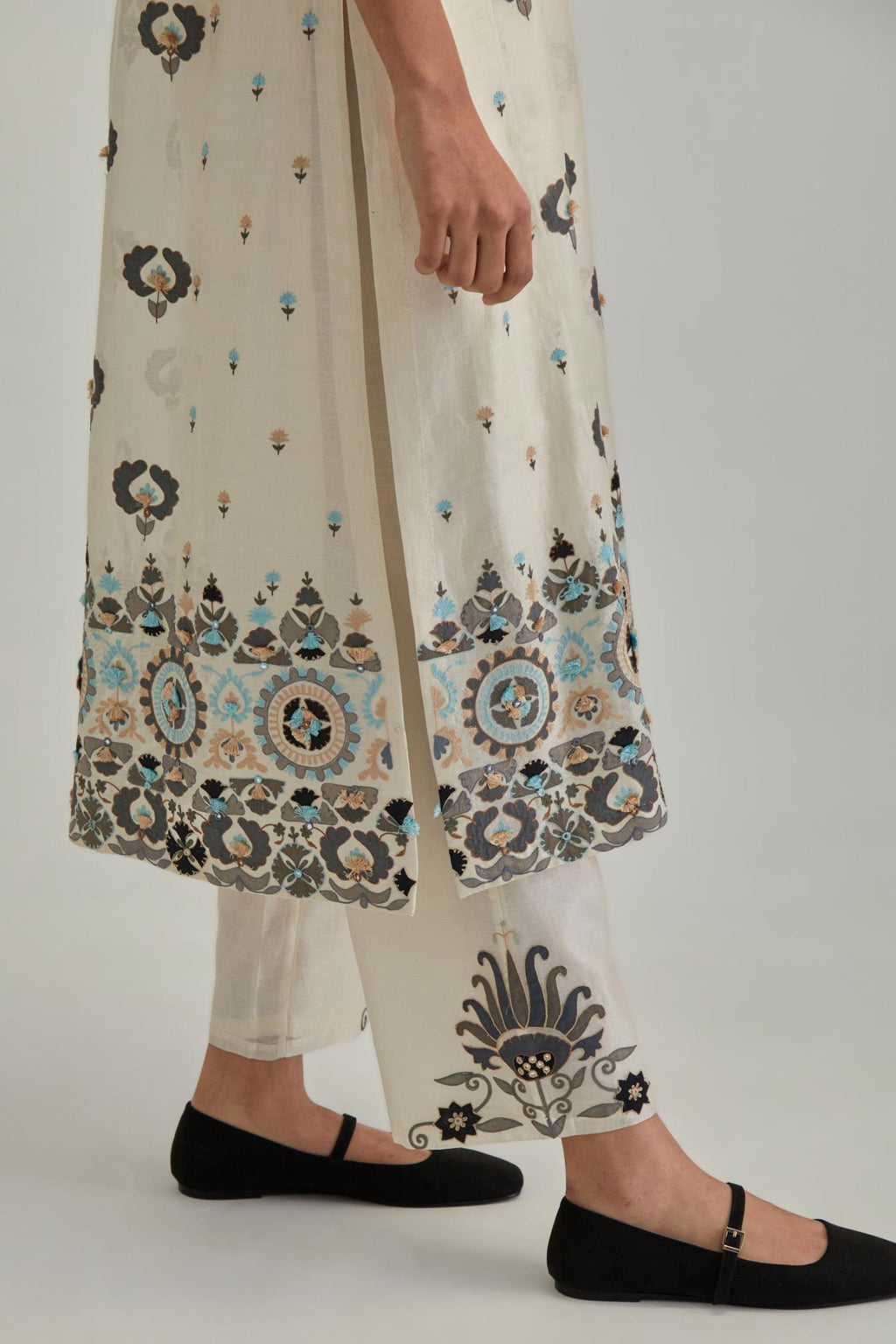 Off White straight kurta, fully embroidered with appliqué flowers, earthy-coloured Aari thread work and silk tassels.