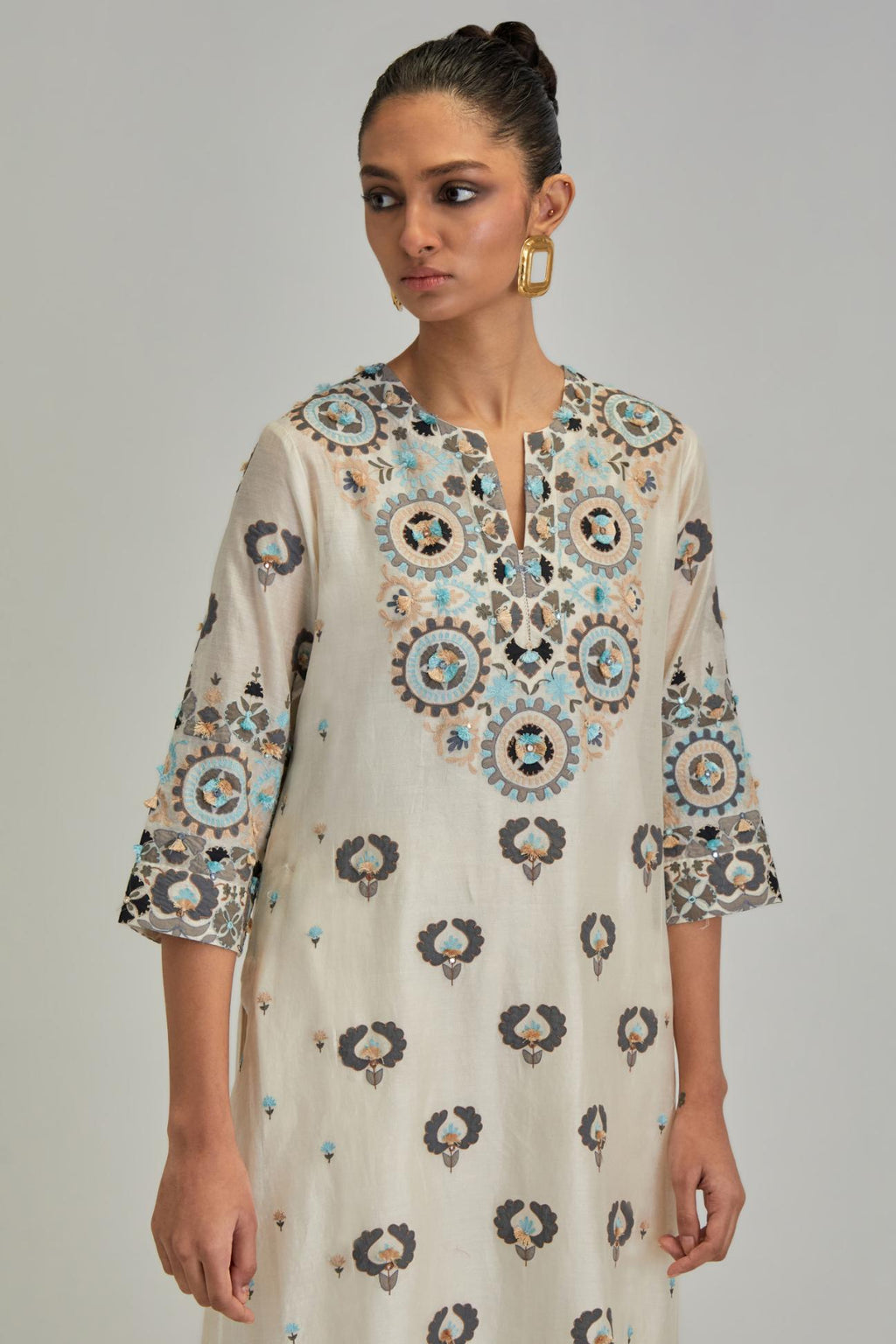 Off White straight kurta, fully embroidered with appliqué flowers, earthy-coloured Aari thread work and silk tassels.