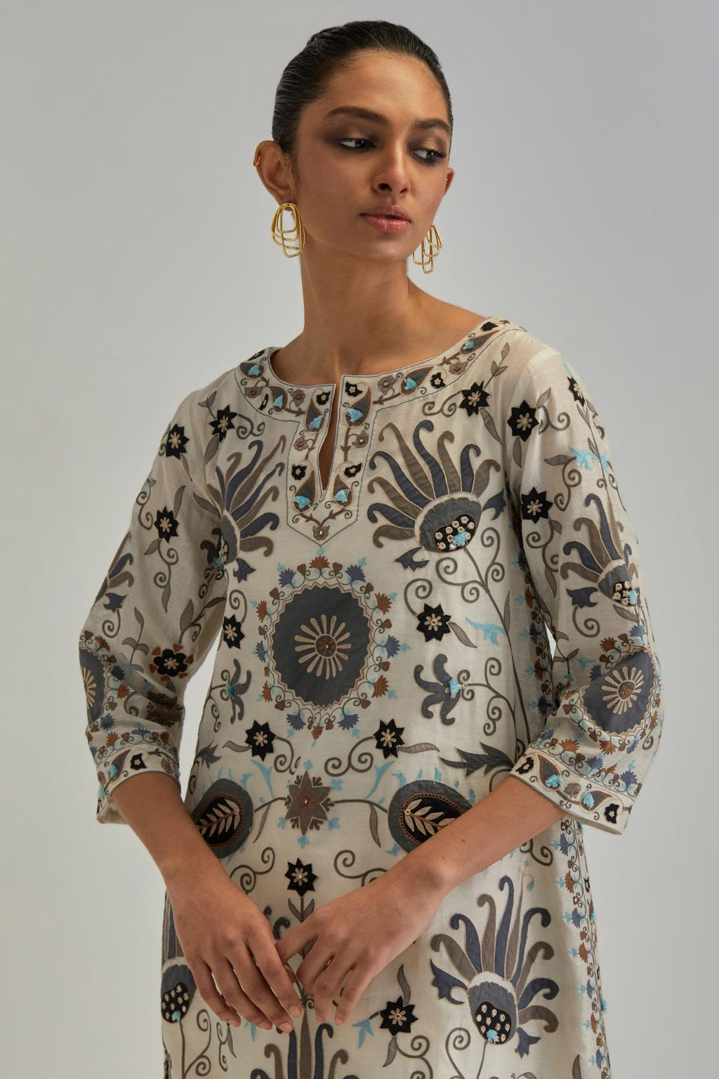 Off White short A-line silk Chanderi kurta set, fully embroidered with earthy coloured appliqué with Aari thread work and silk tassels.