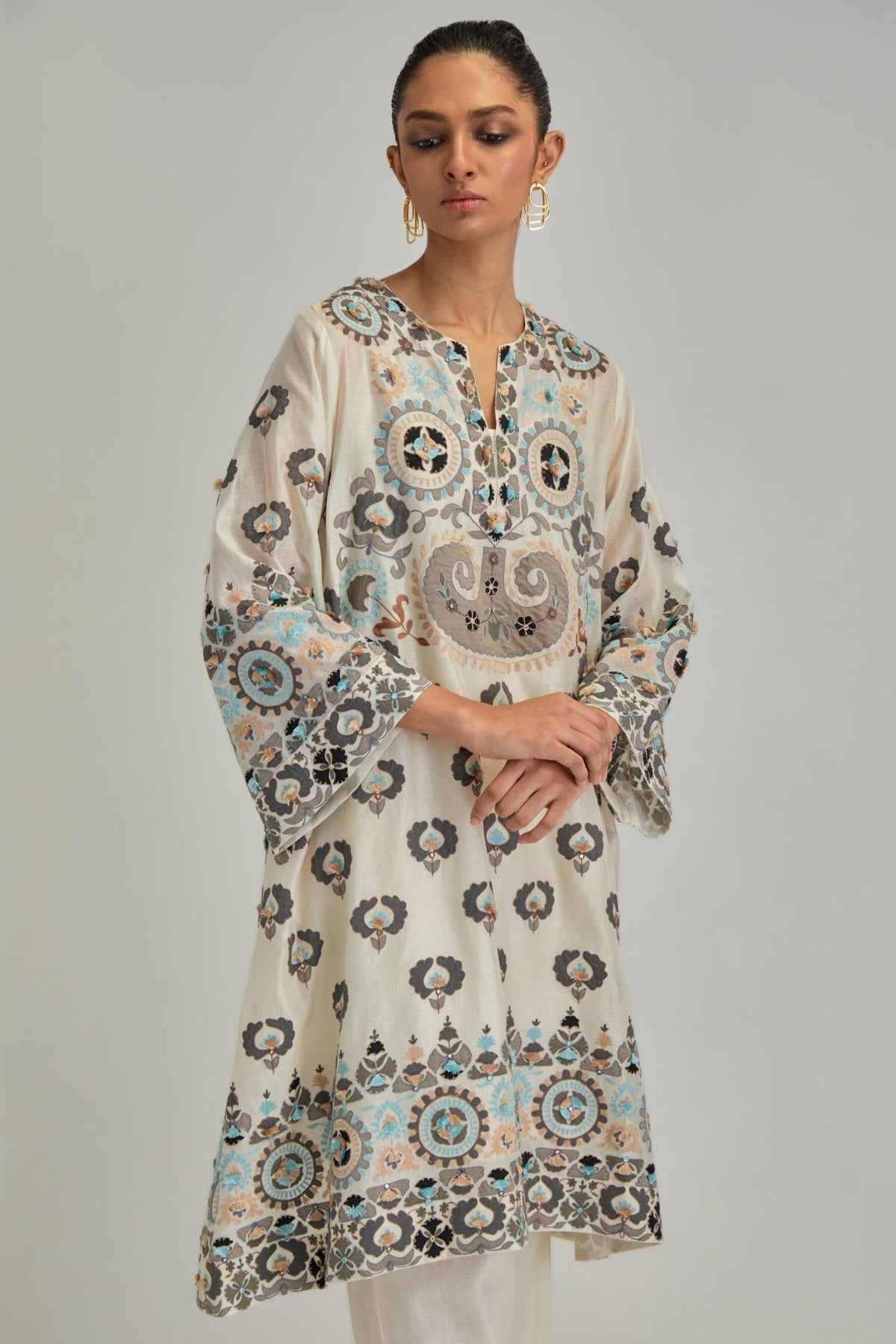 Off White silk Chanderi straight hem mid-length abha style kurta set with bold appliqué embroidery along with earthy-coloured Aari thread work and tassels.