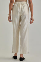 Off white silk Chanderi straight pants with earthy coloured appliqué at hem.